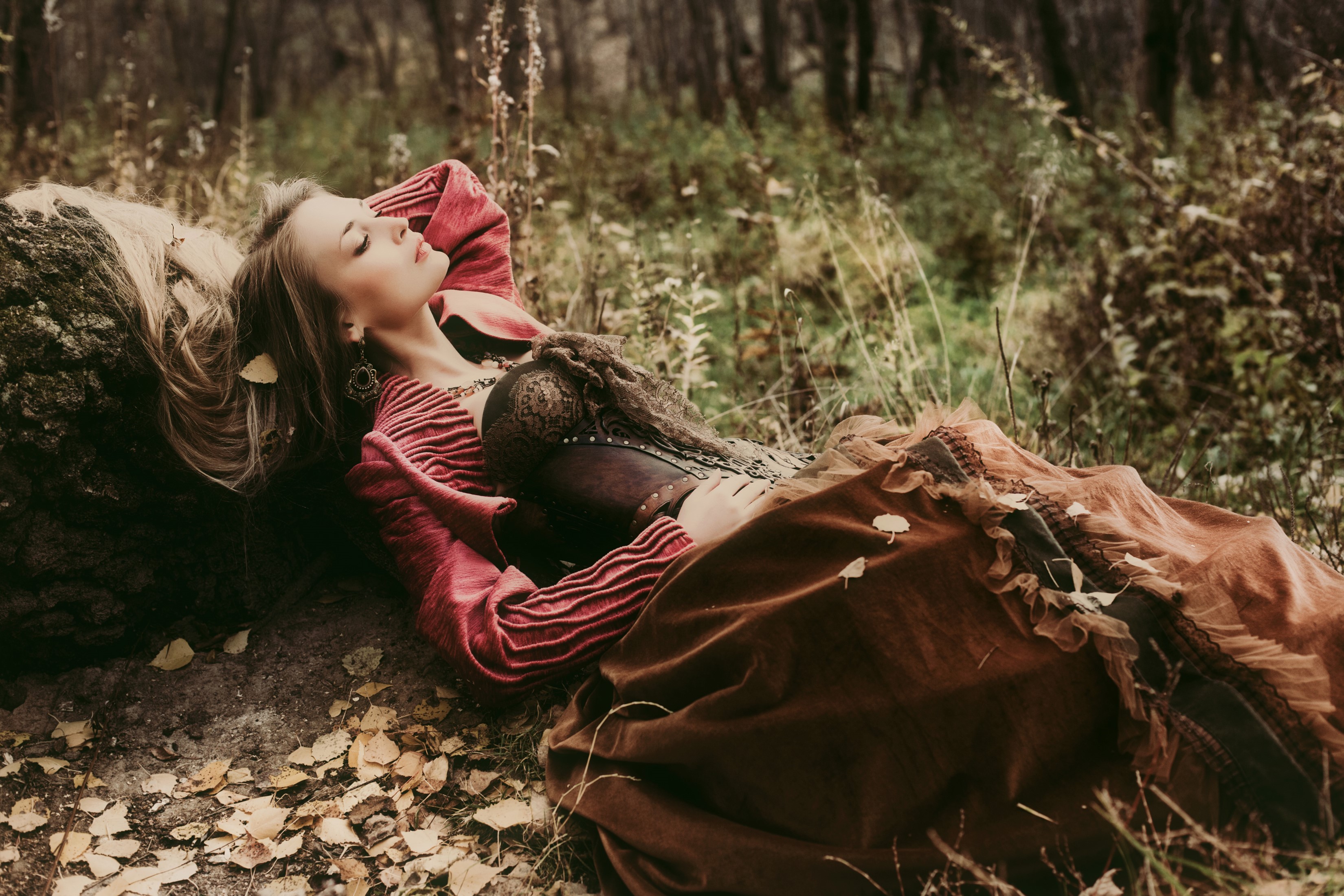 Woman in corset and dress lying on log in forest HD Wallpaper