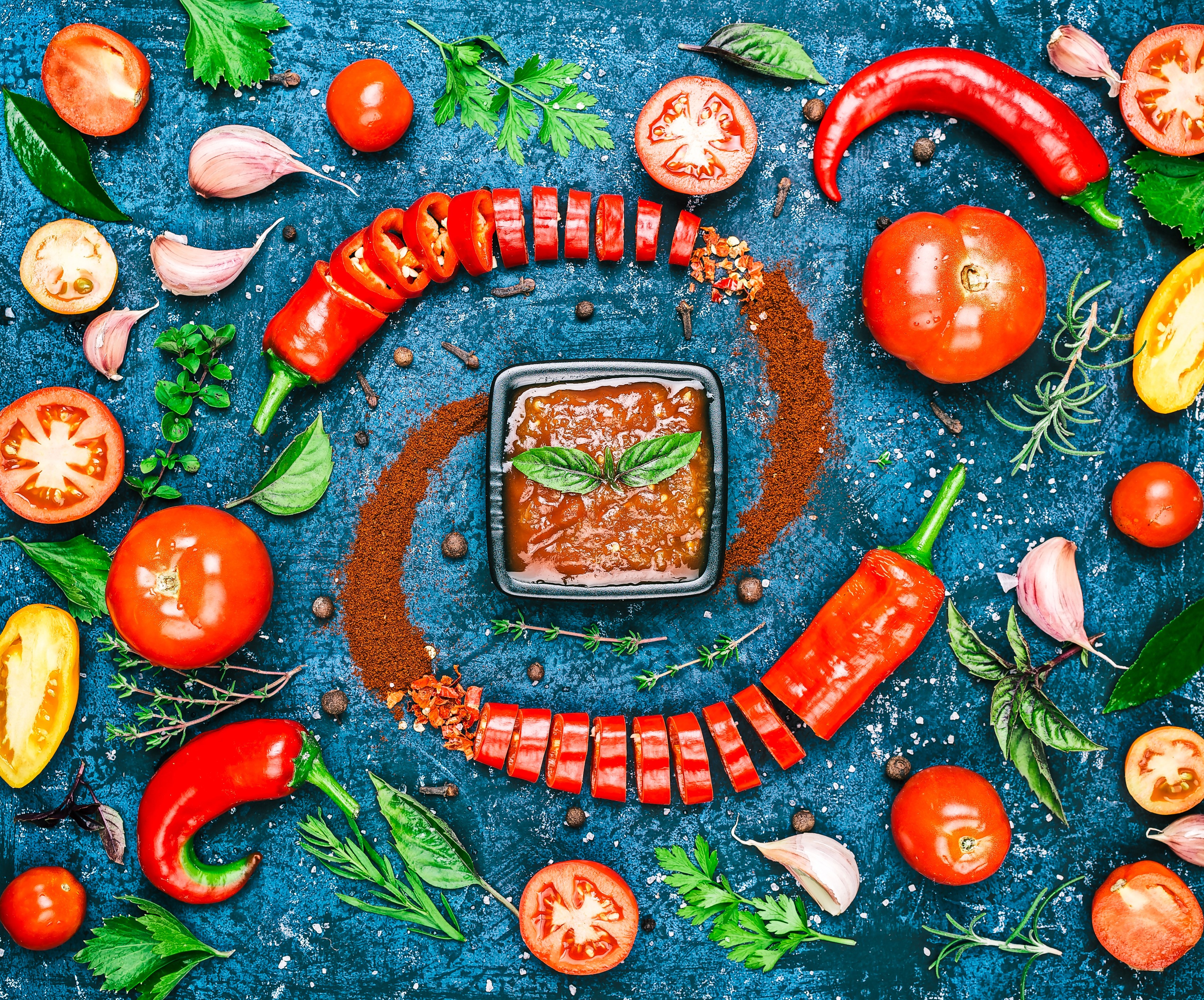 Tomatoes, chili peppers, garlic, and sauce on a blue background HD Wallpaper
