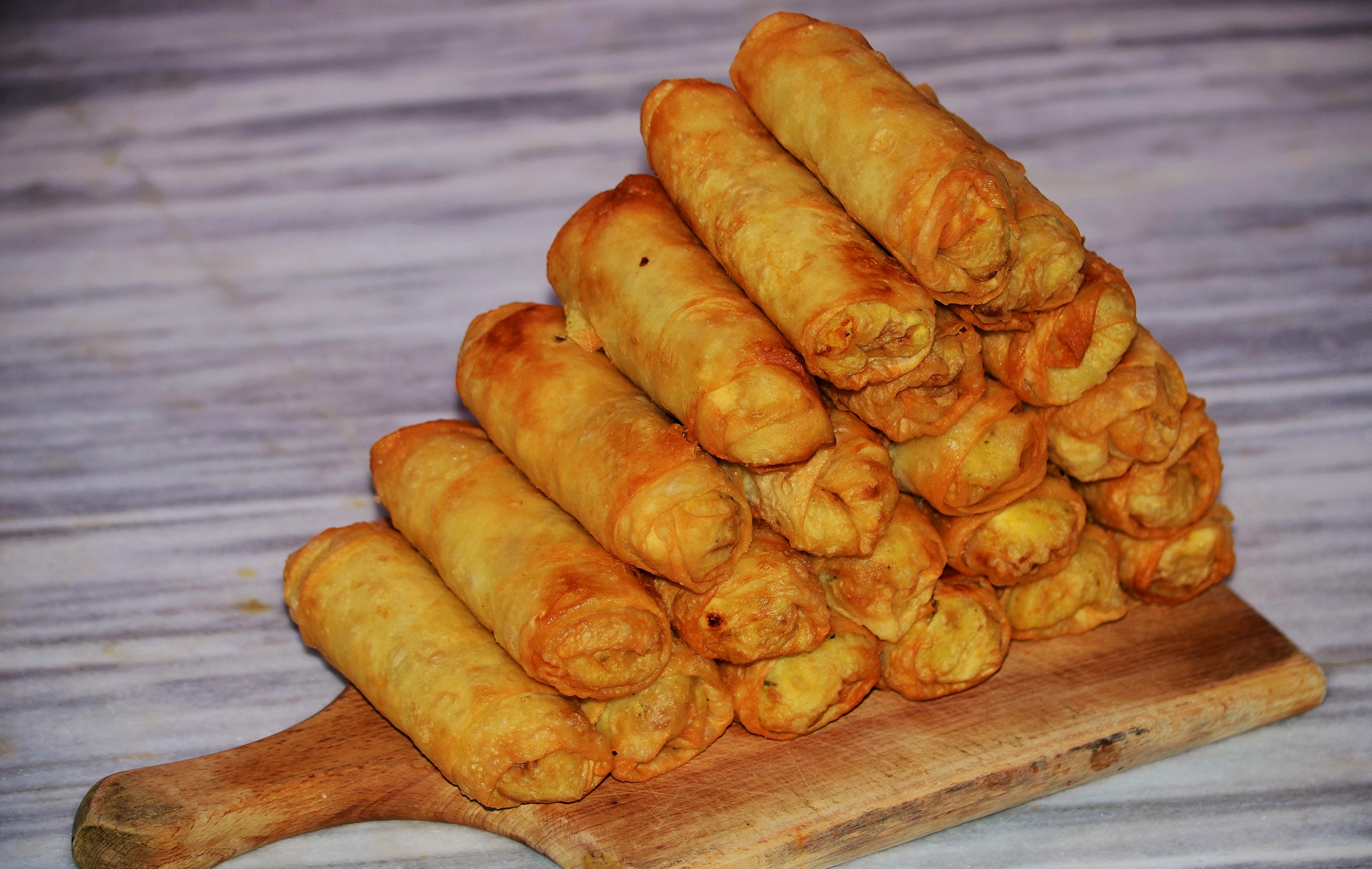 Fried spring rolls stacked on a cutting board HD Wallpaper