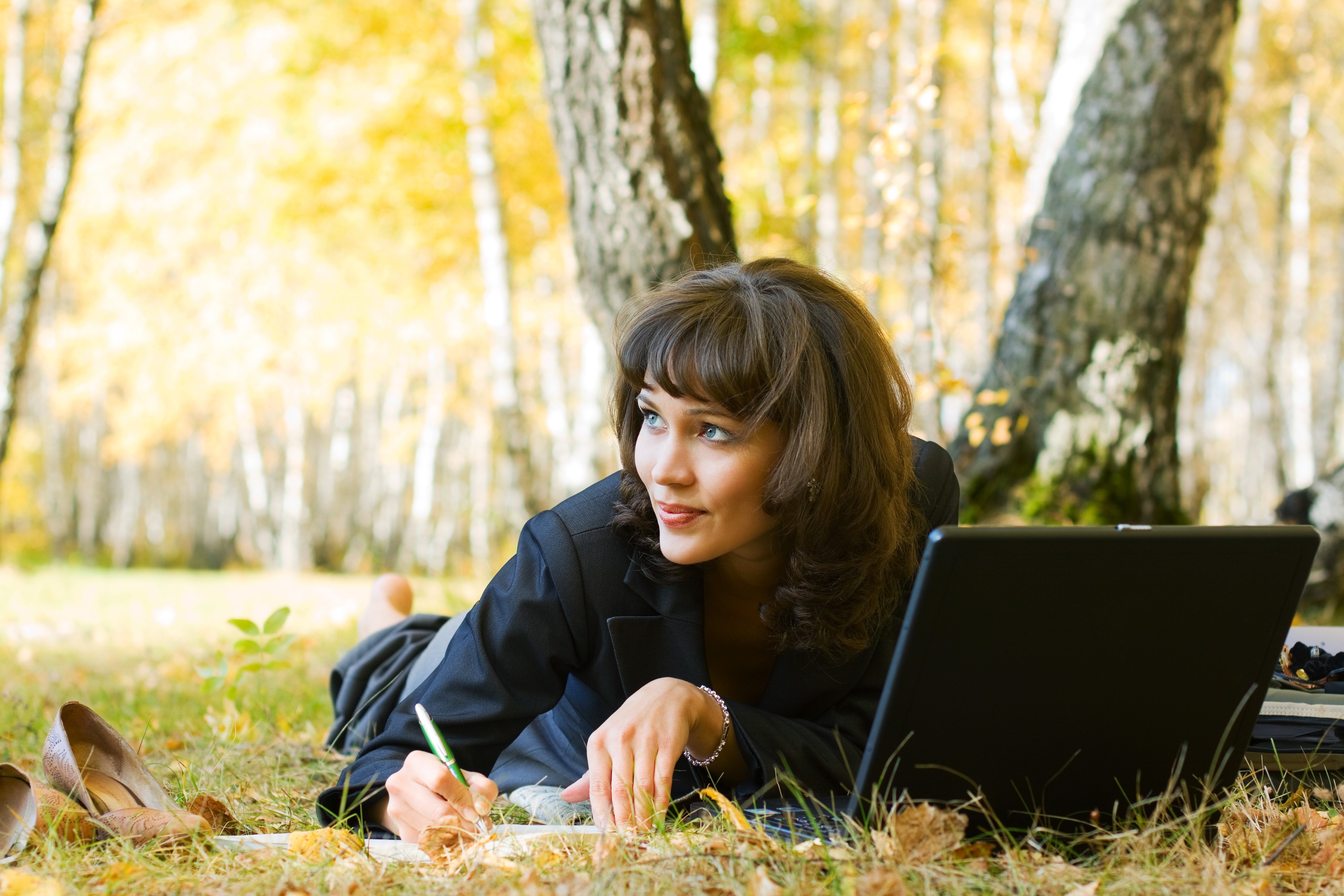 Brunette girl with laptop lying in autumn park HD Wallpaper