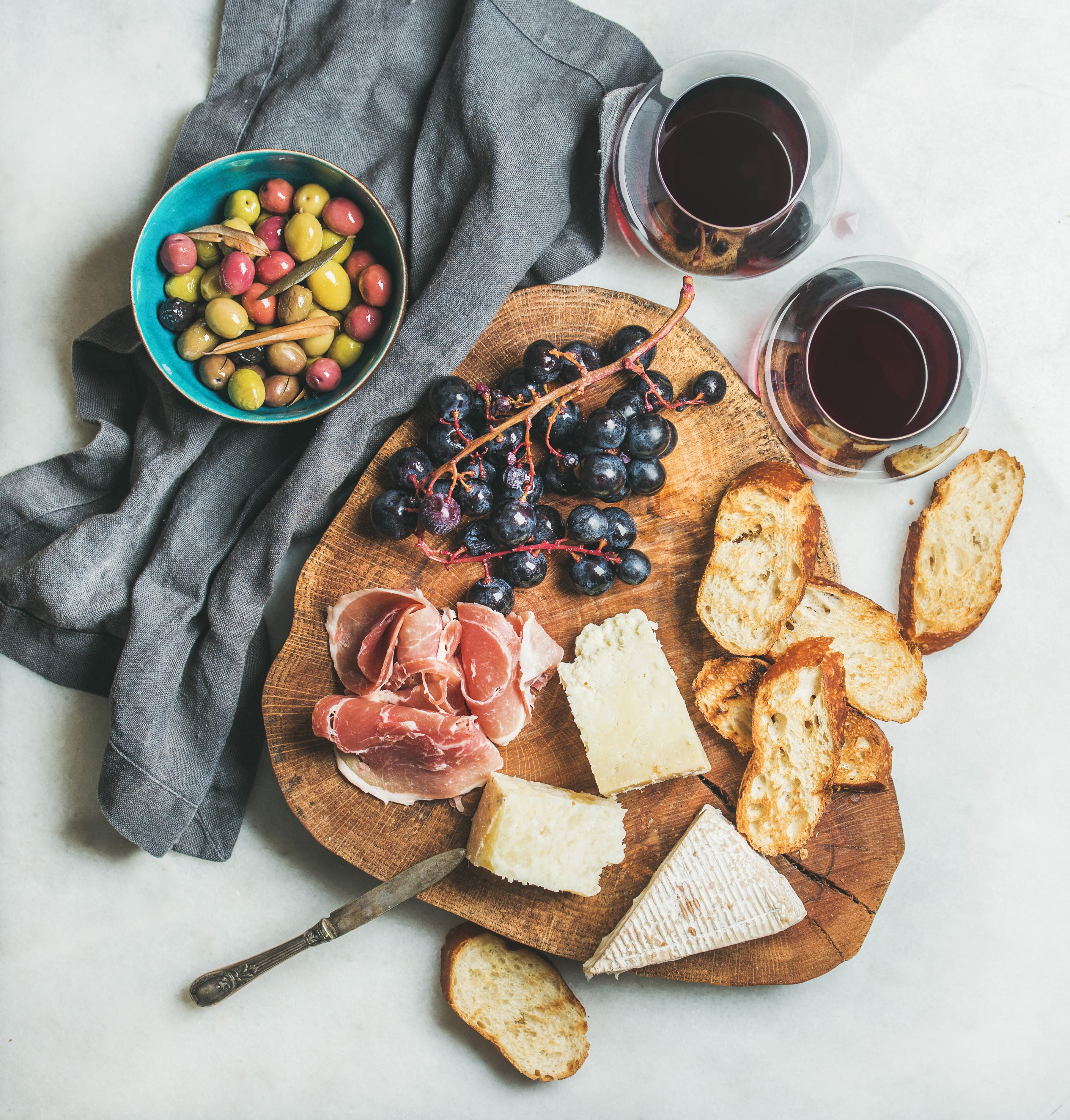 Charcuterie board with cheese, ham, olives, grapes, and bread with wine HD Wallpaper