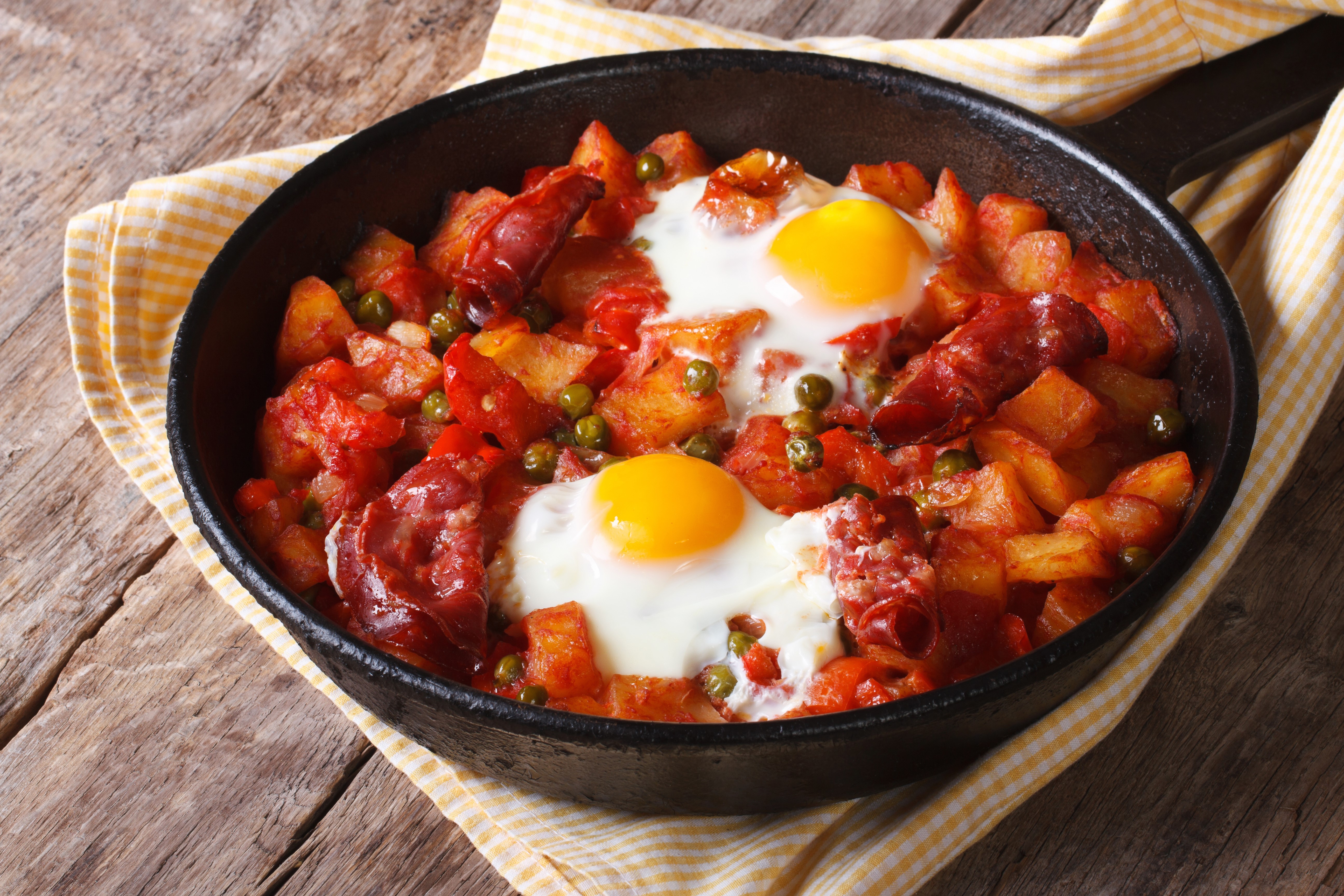 Fried eggs with potatoes, chorizo, and peas in a frying pan HD Wallpaper