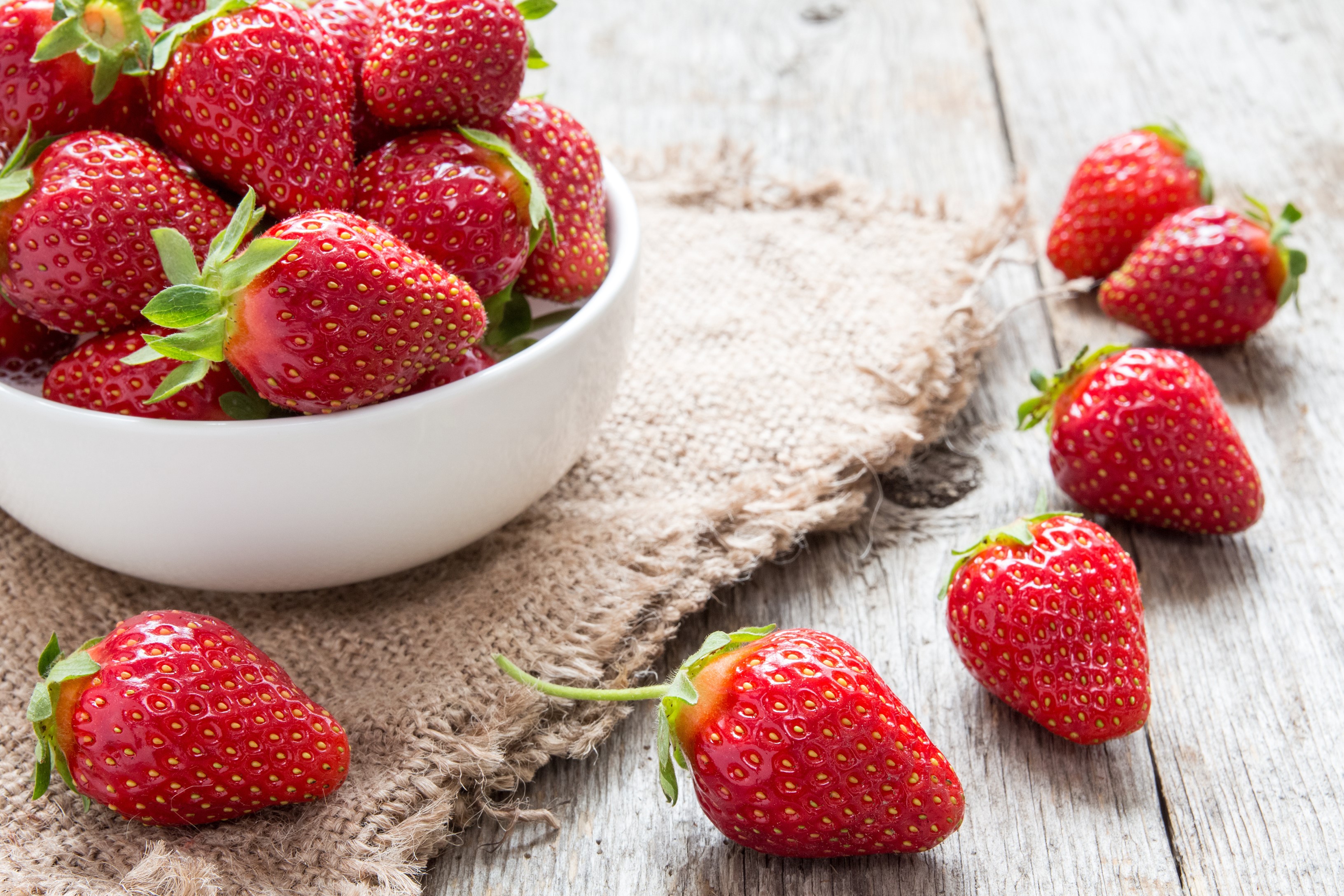 Strawberries in a bowl on a wooden table HD Wallpaper