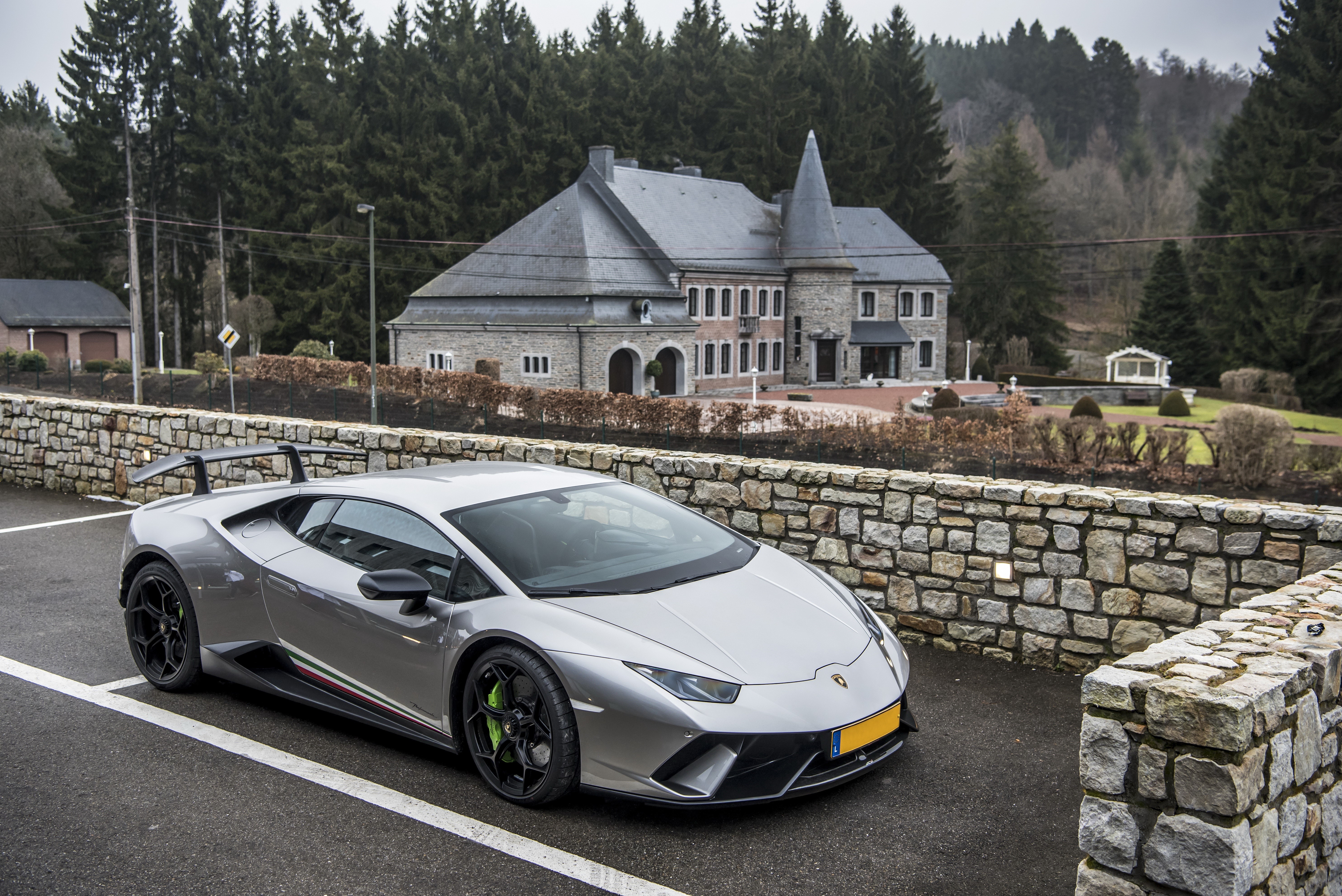 Grey Lamborghini Performante Huracan parked near a stone wall and mansion HD Wallpaper