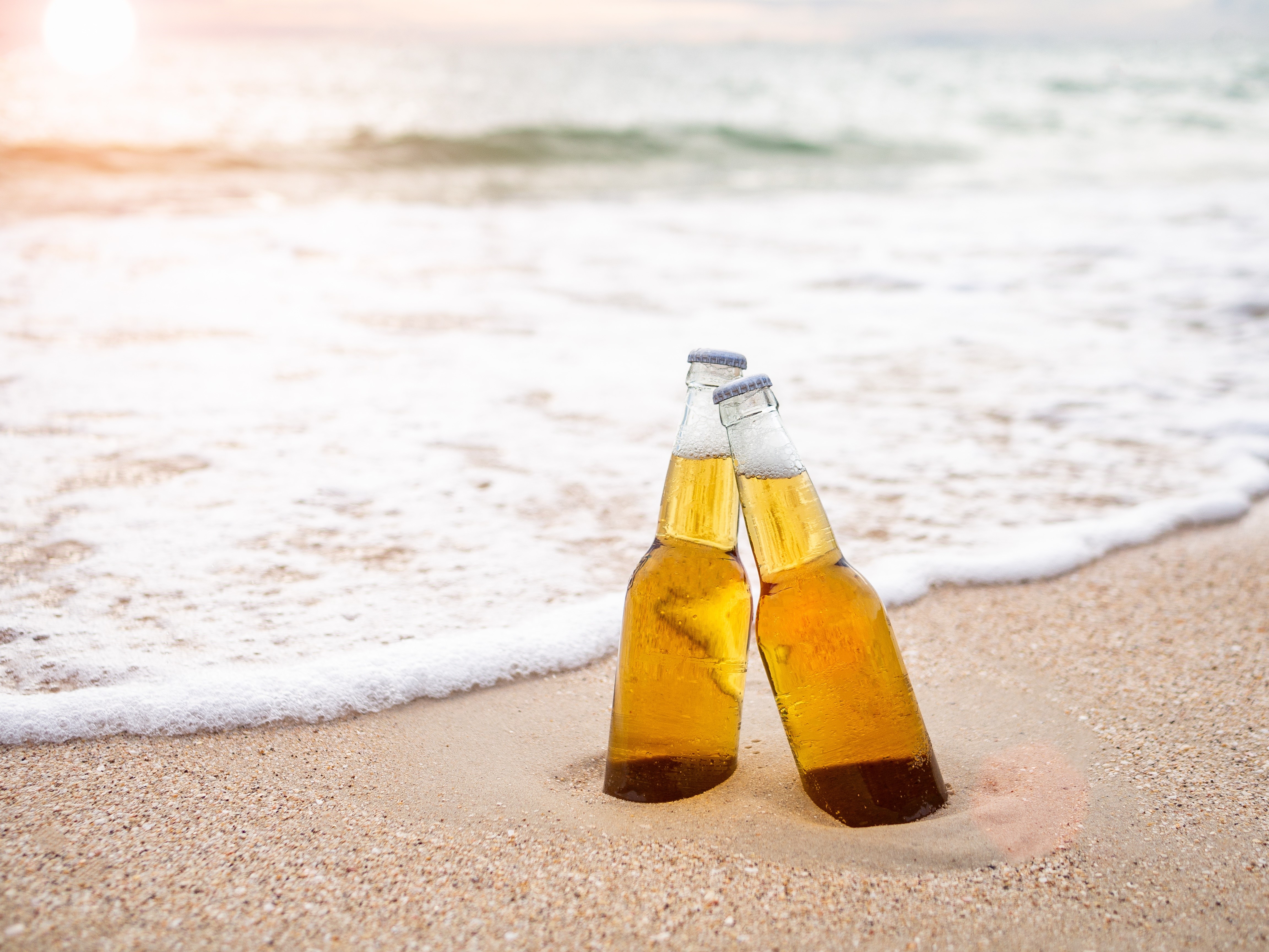 Two beer bottles on a beach HD Wallpaper