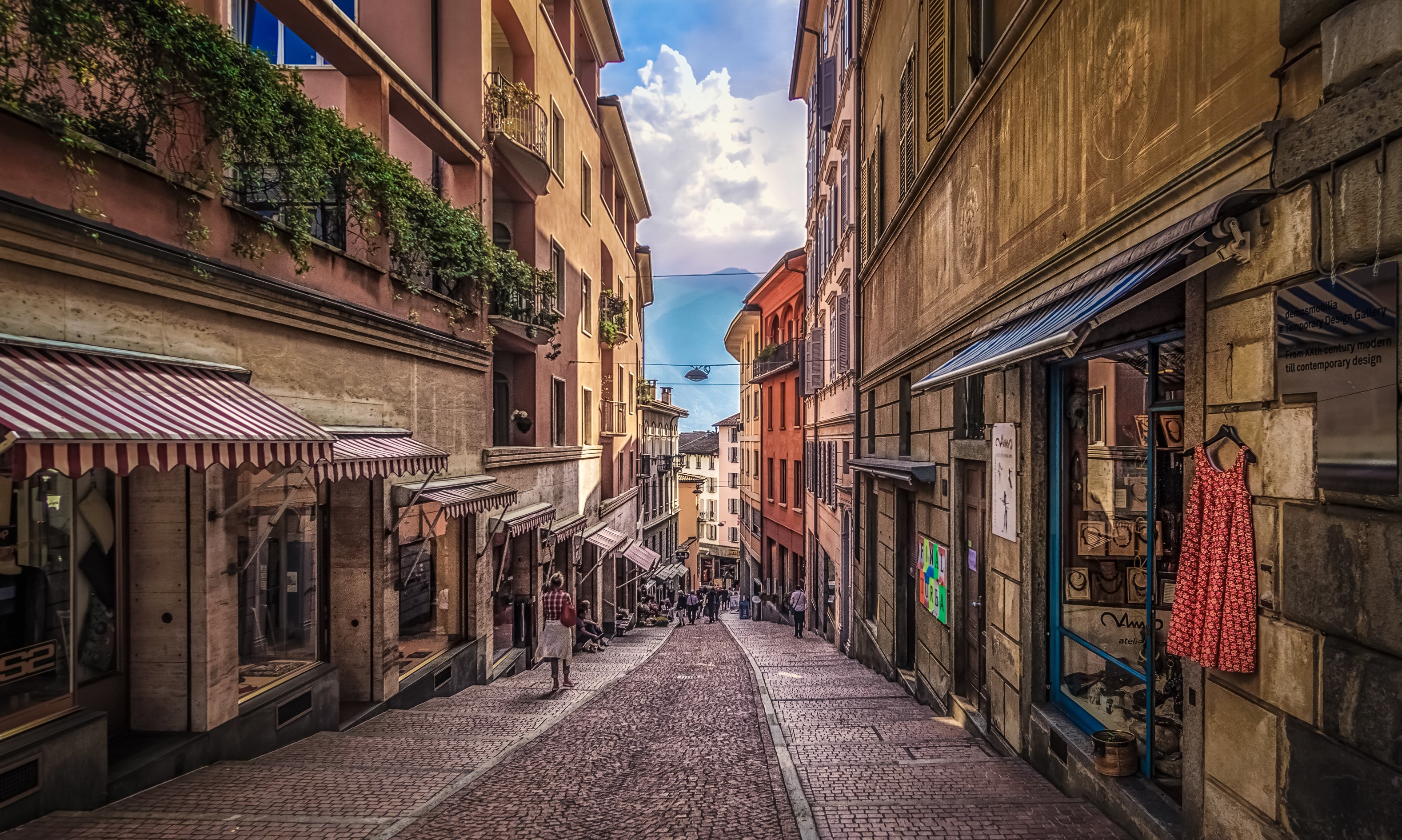 Street in Lugano, Switzerland with buildings and a lake view HD Wallpaper