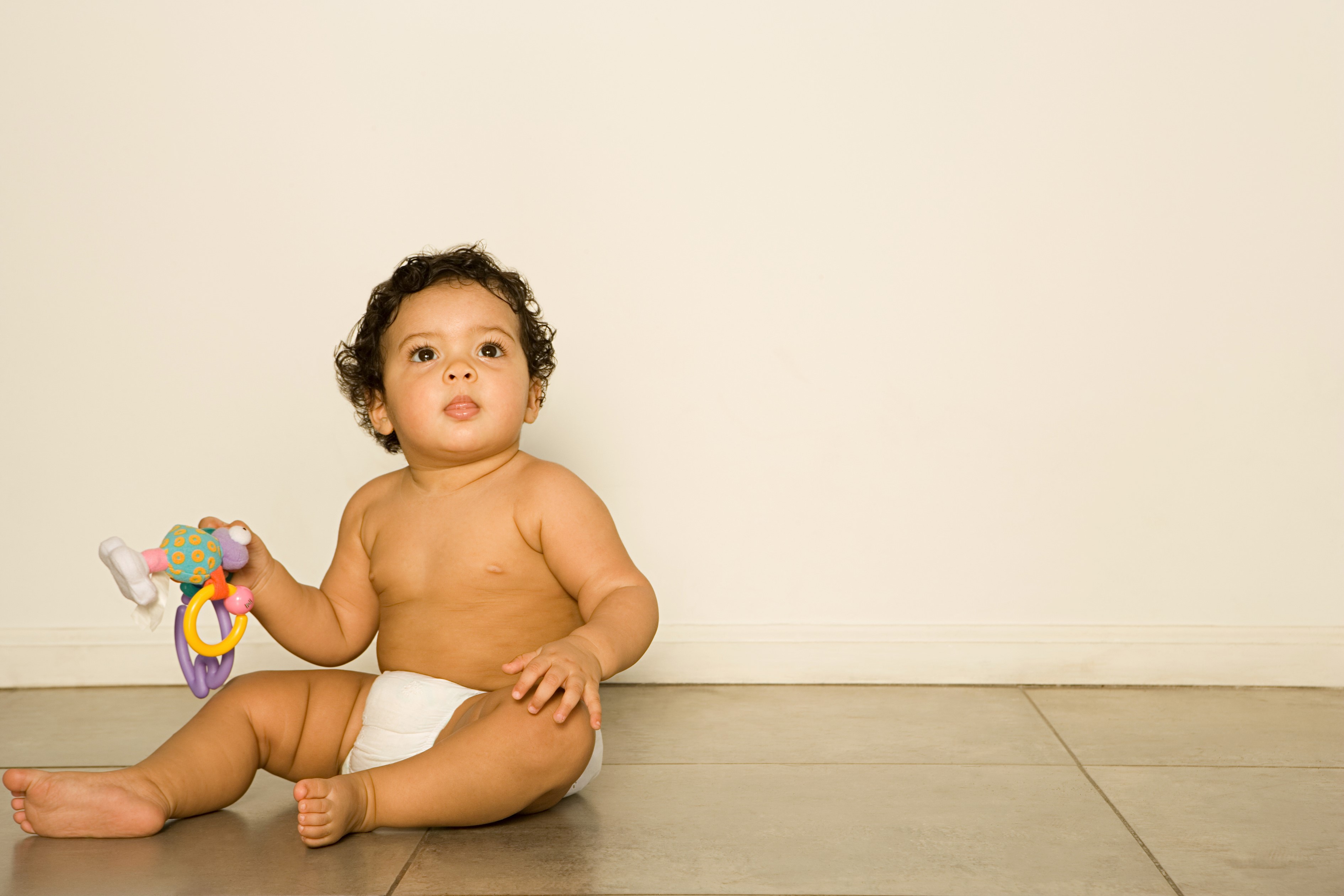 Baby sitting on floor holding a toy HD Wallpaper