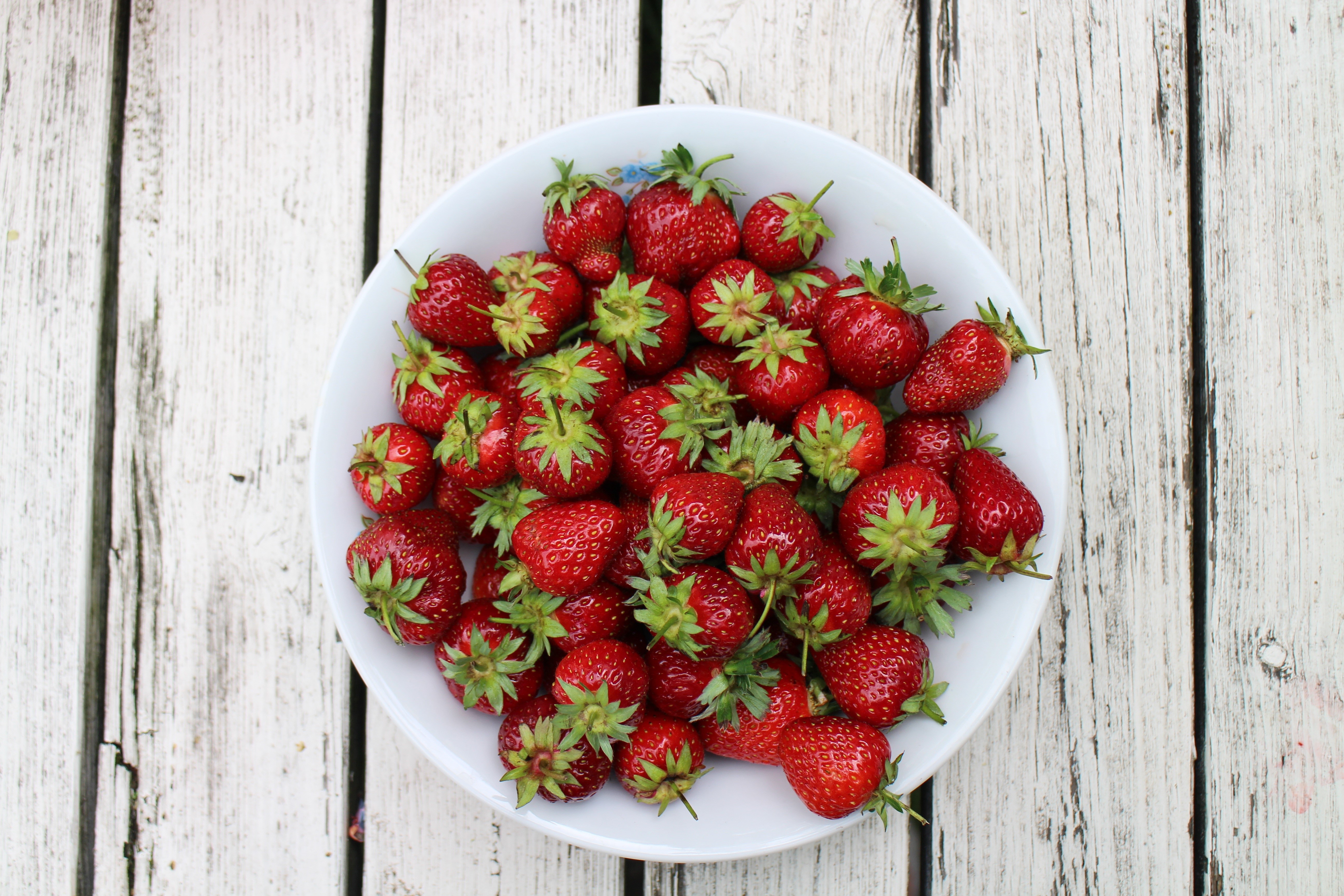 Strawberries in a white plate on a wooden table HD Wallpaper