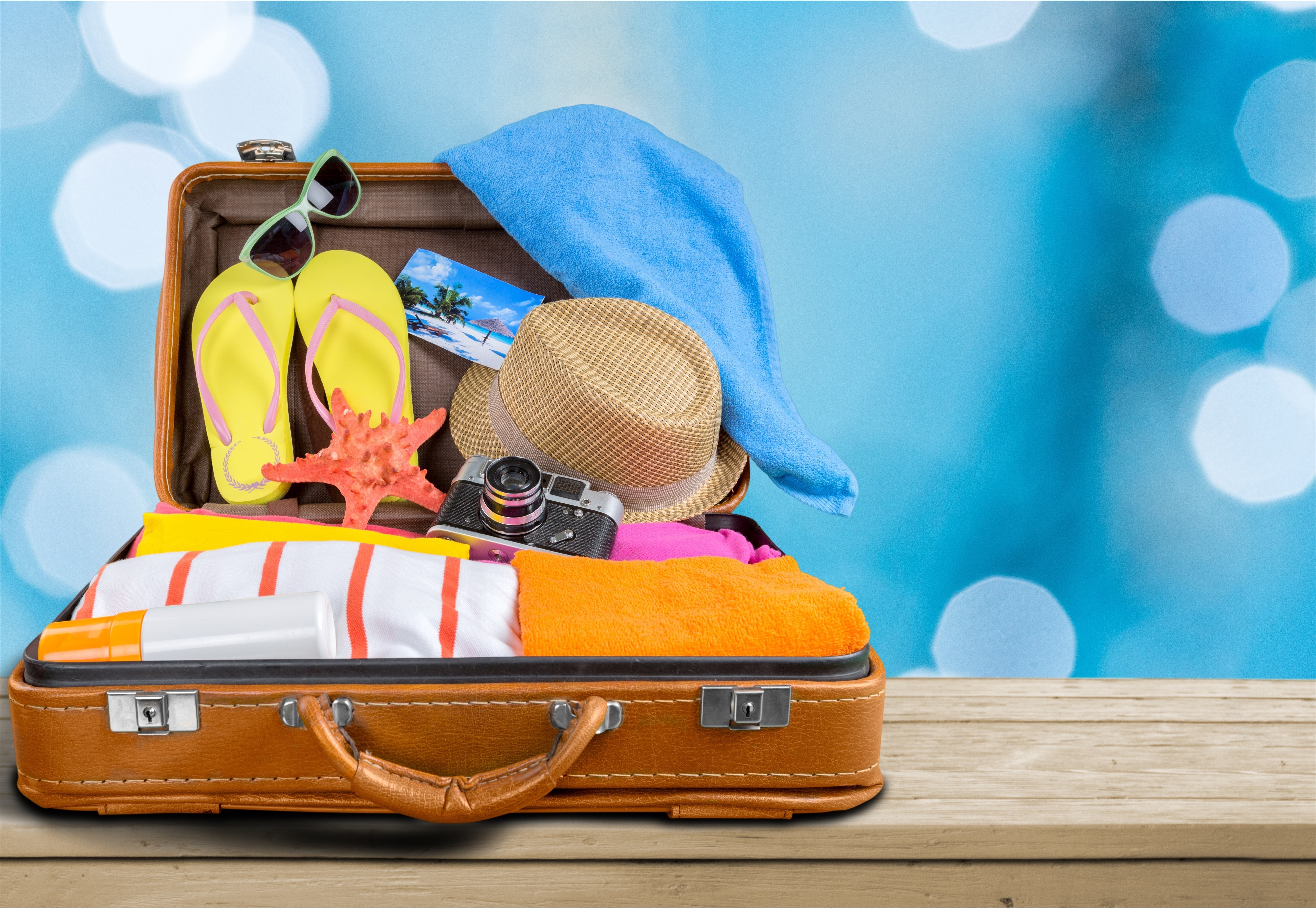 Open suitcase packed for vacation with beach items HD Wallpaper