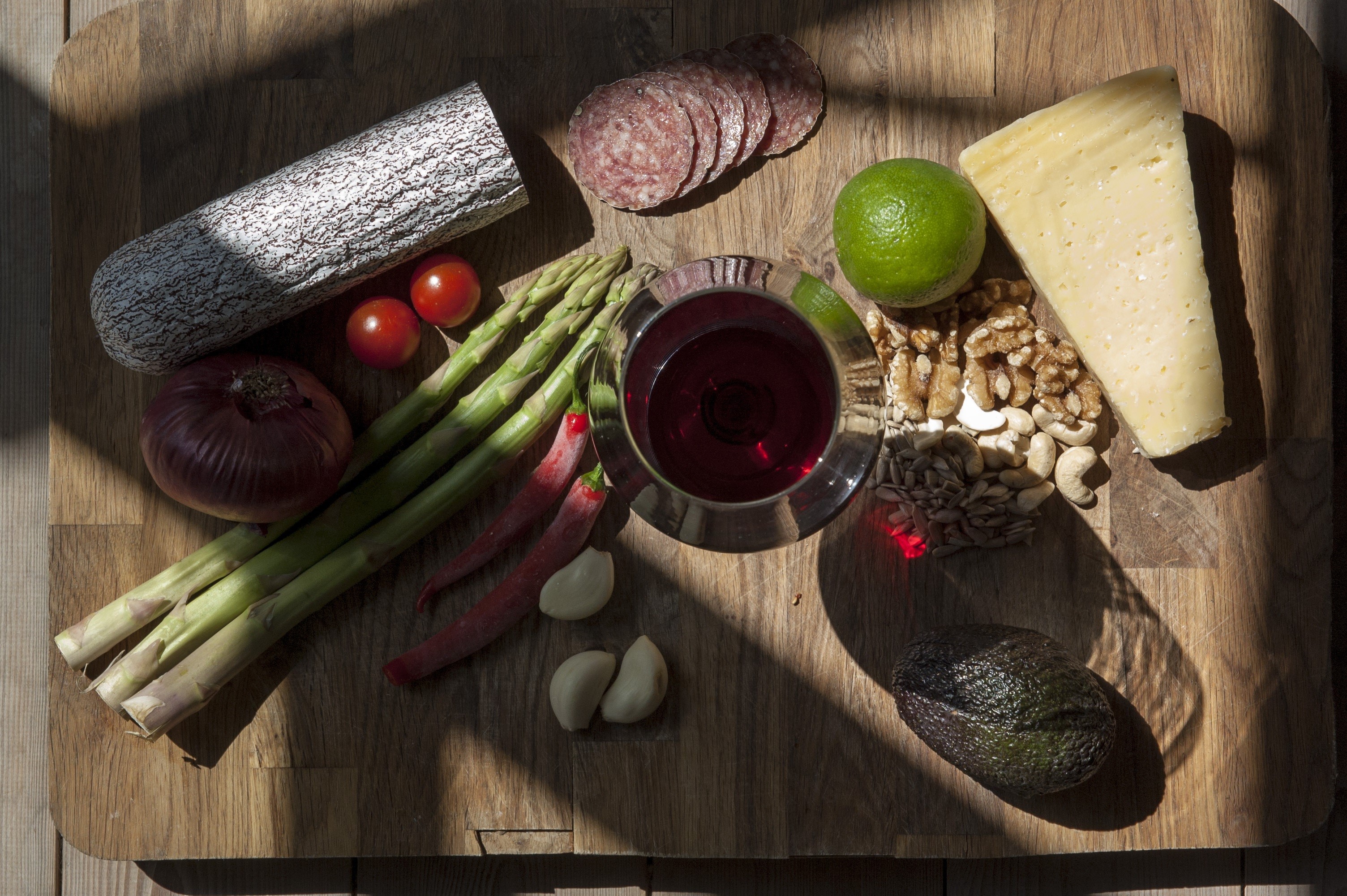 Charcuterie board with sausage, cheese, wine, and vegetables HD Wallpaper