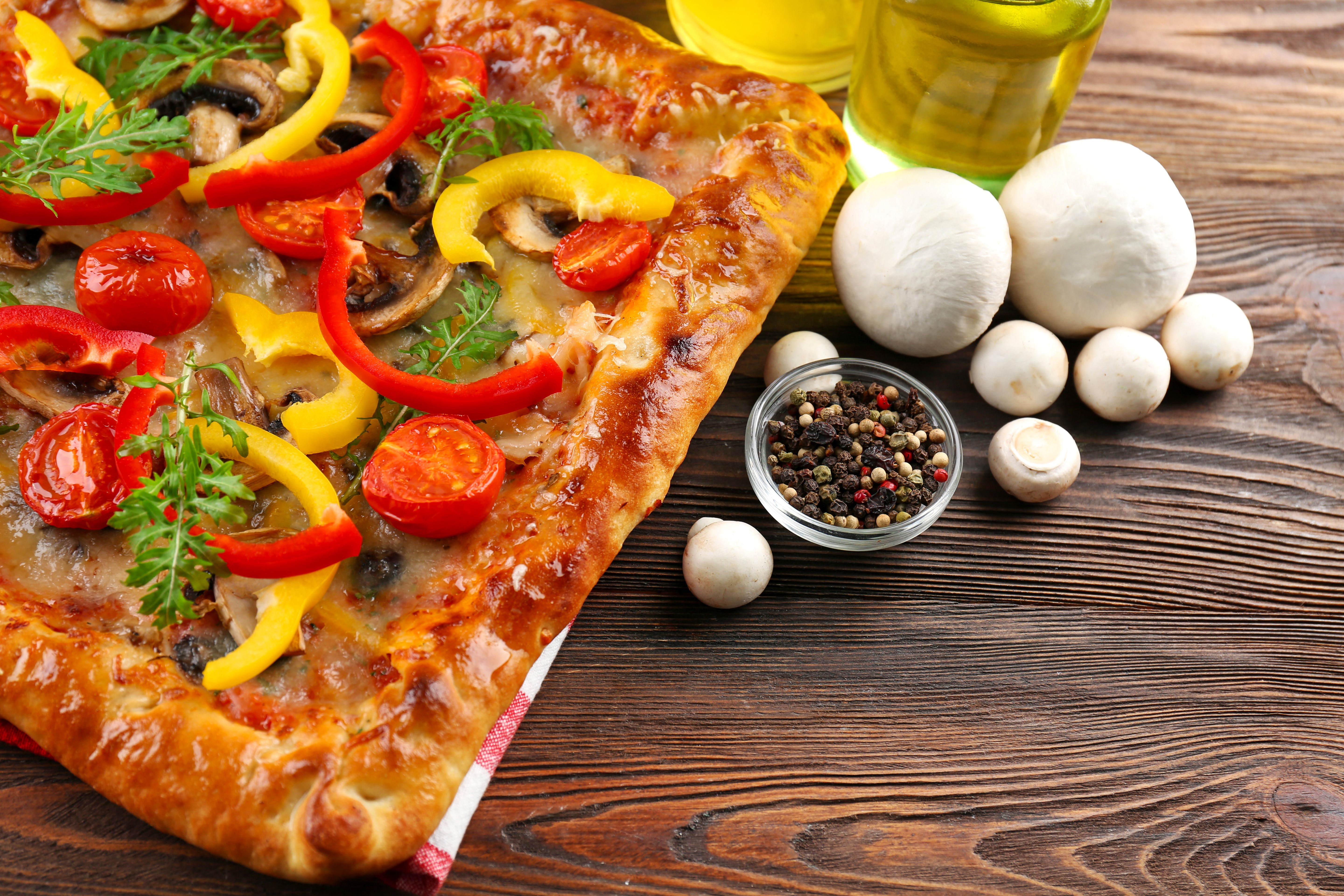 Rectangular pizza with mushrooms, peppers, and tomatoes on a wooden table HD Wallpaper