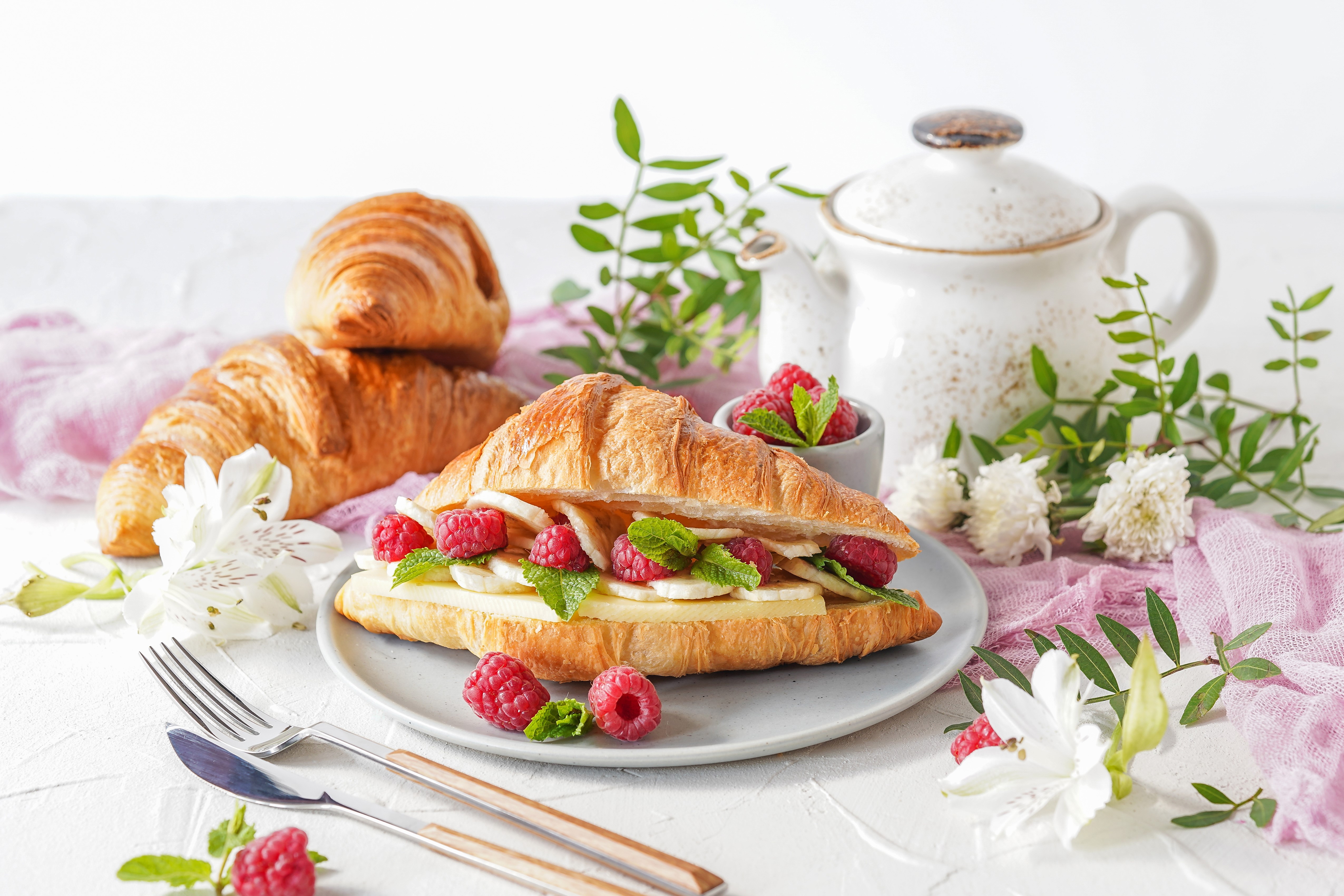Croissant sandwich with raspberries, bananas, and mint, served with croissants and a kettle HD Wallpaper