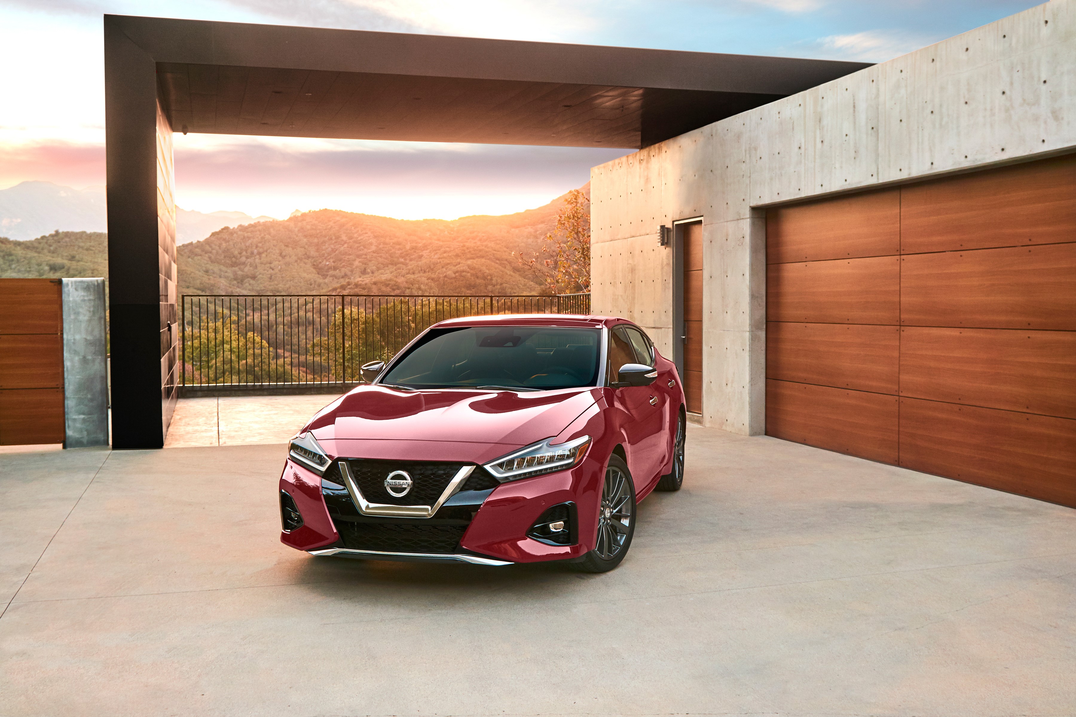 Red Nissan Maxima parked in modern driveway HD Wallpaper