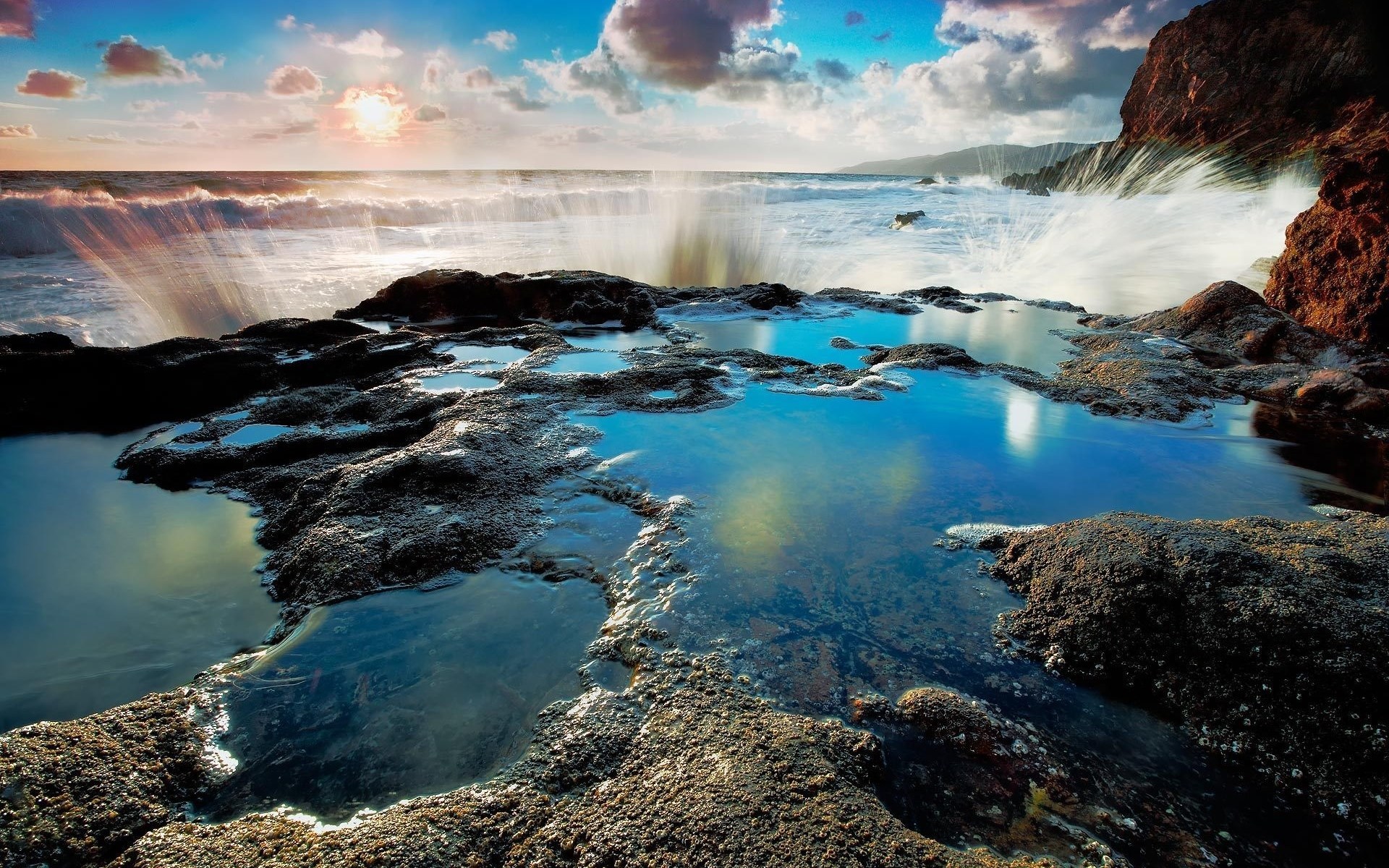 Waves crashing on rocky shore with tide pools at sunset HD Wallpaper