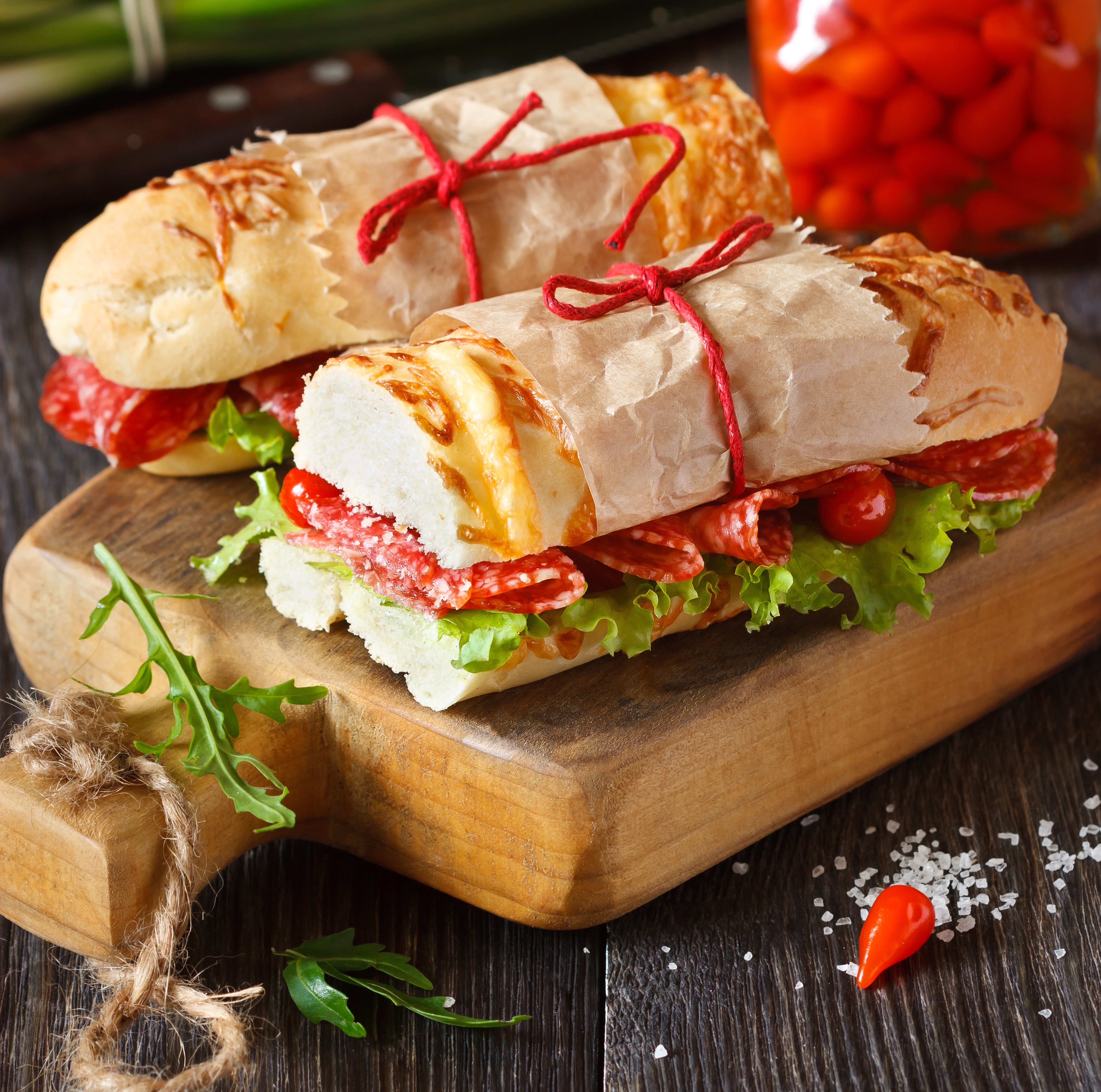 Two sandwiches with salami and lettuce on a wooden board HD Wallpaper