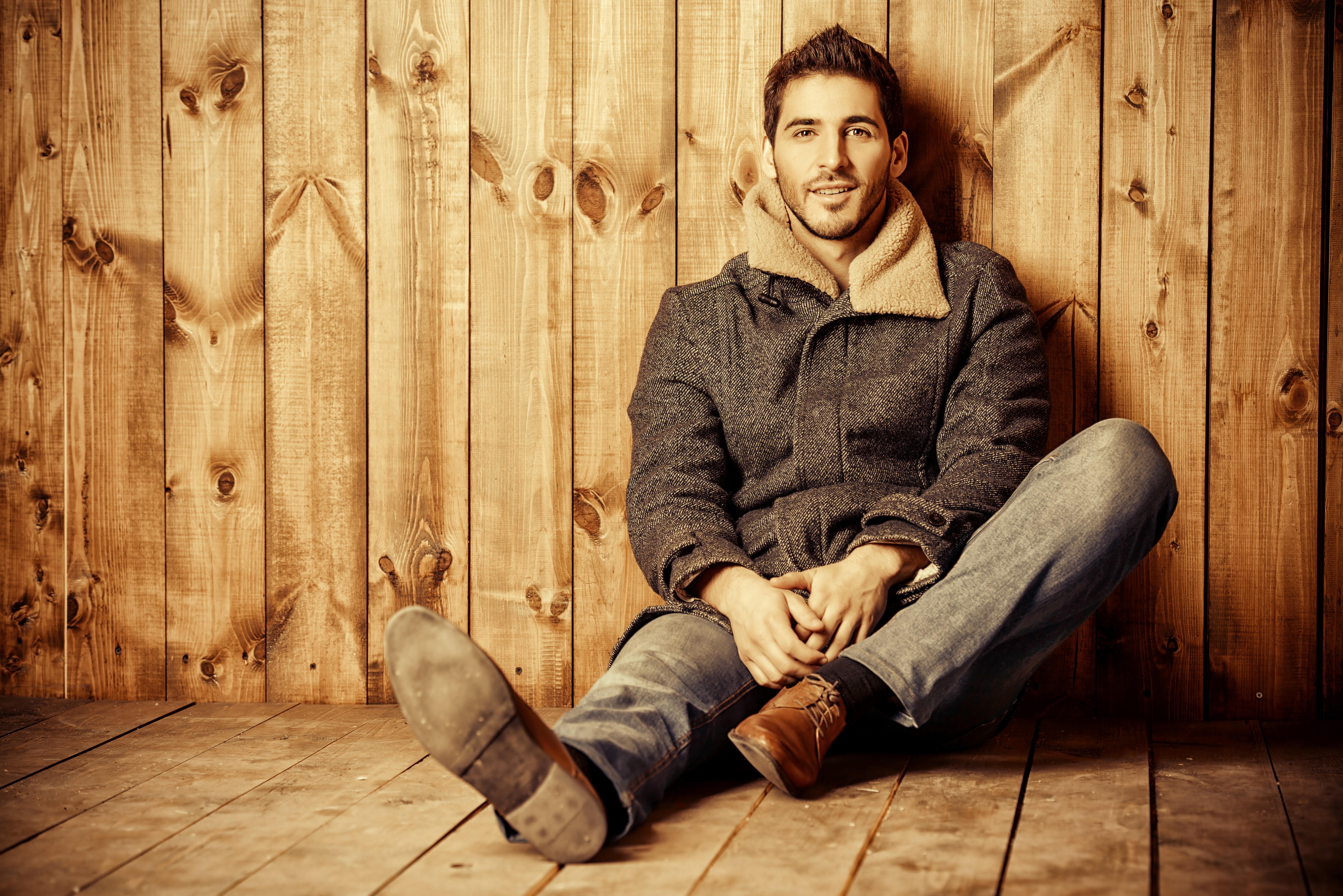 Man in jacket sitting against wood planks HD Wallpaper