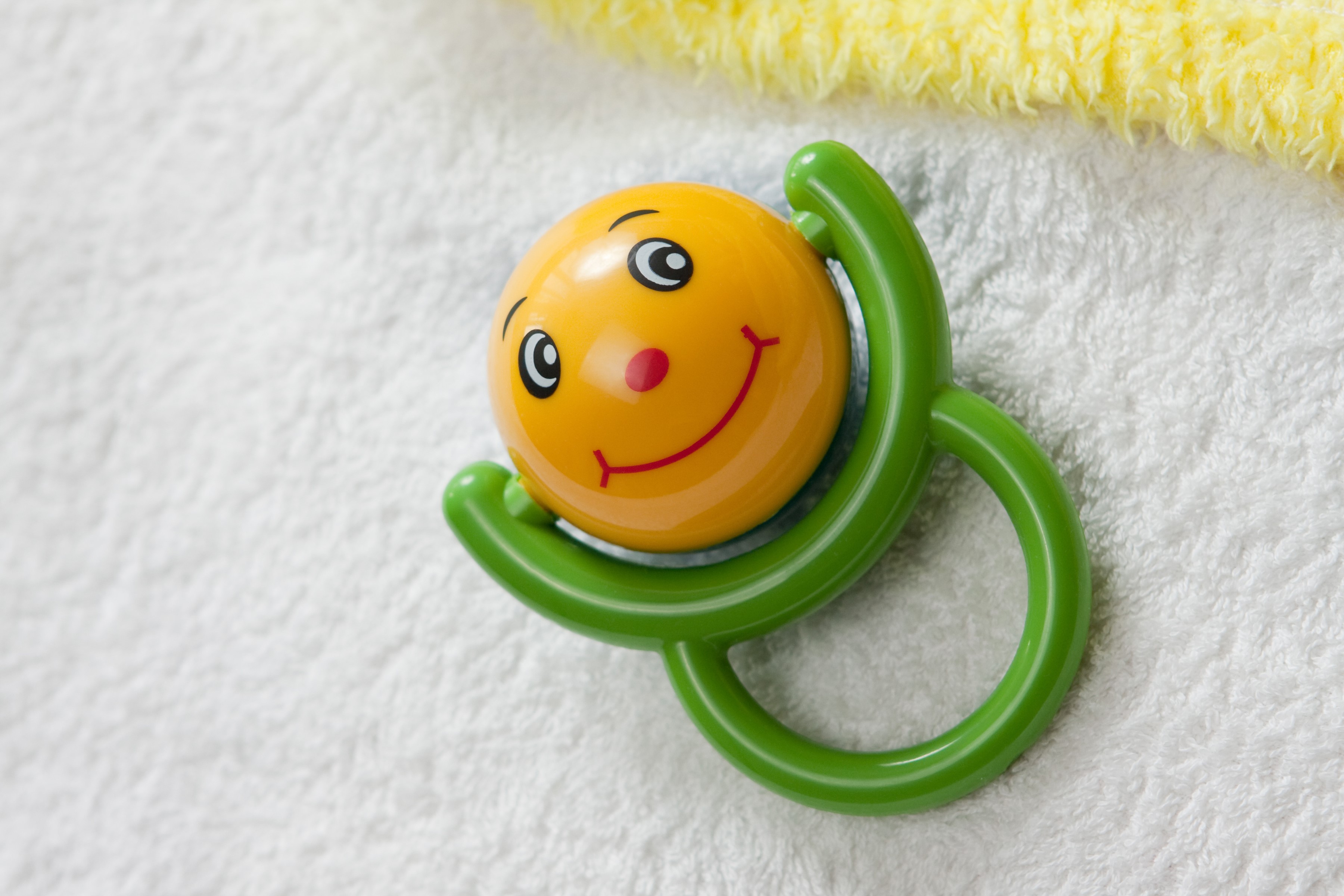 Baby rattle with smiley face on white towel HD Wallpaper