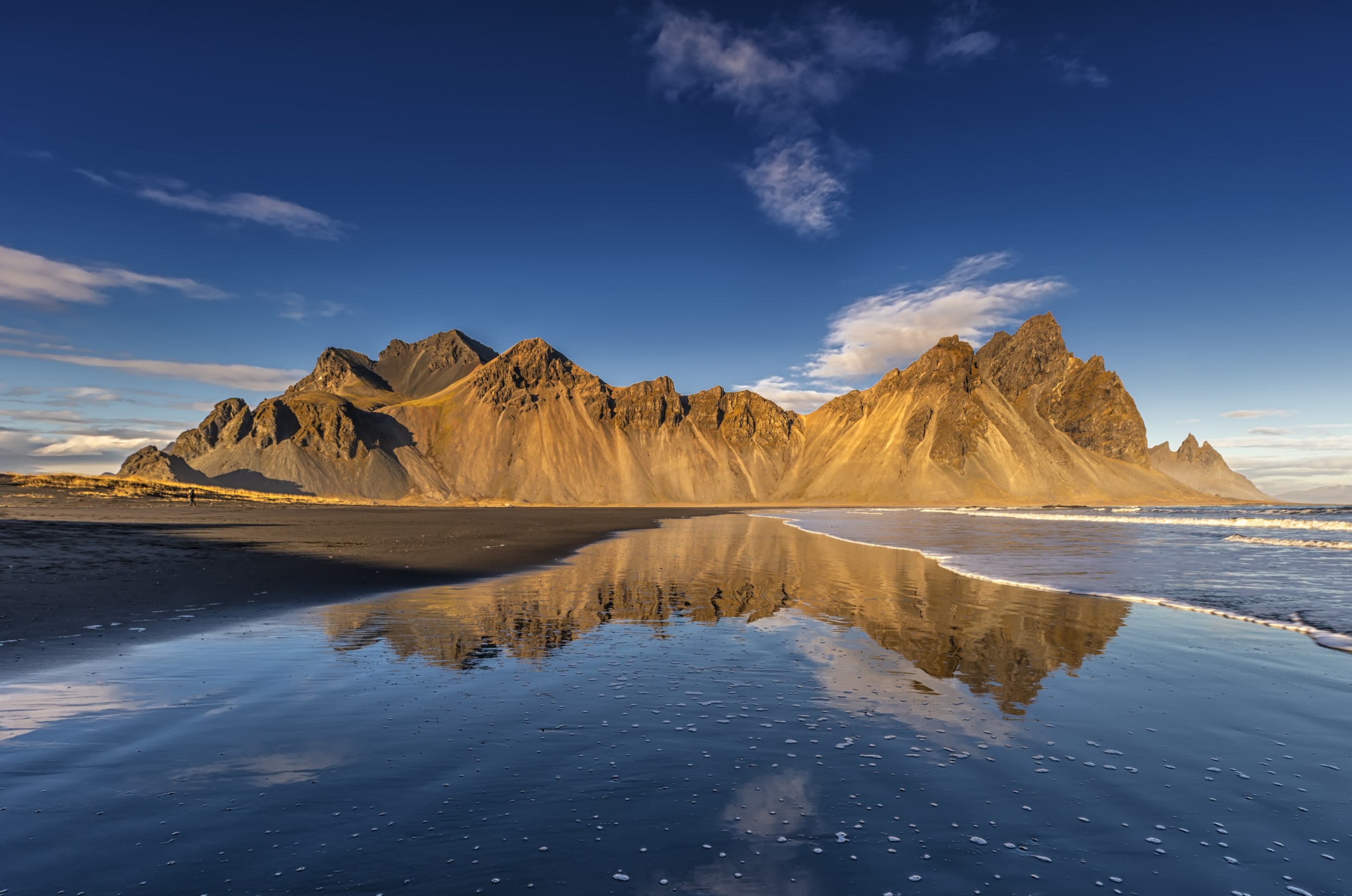 Mountains reflecting in the ocean on a black sand beach in Iceland HD Wallpaper