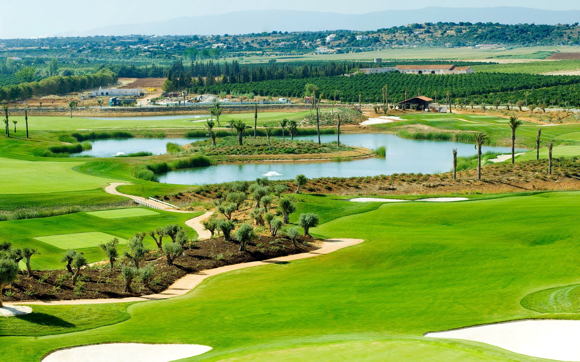 Golf course with a lake and surrounding landscape HD Wallpaper