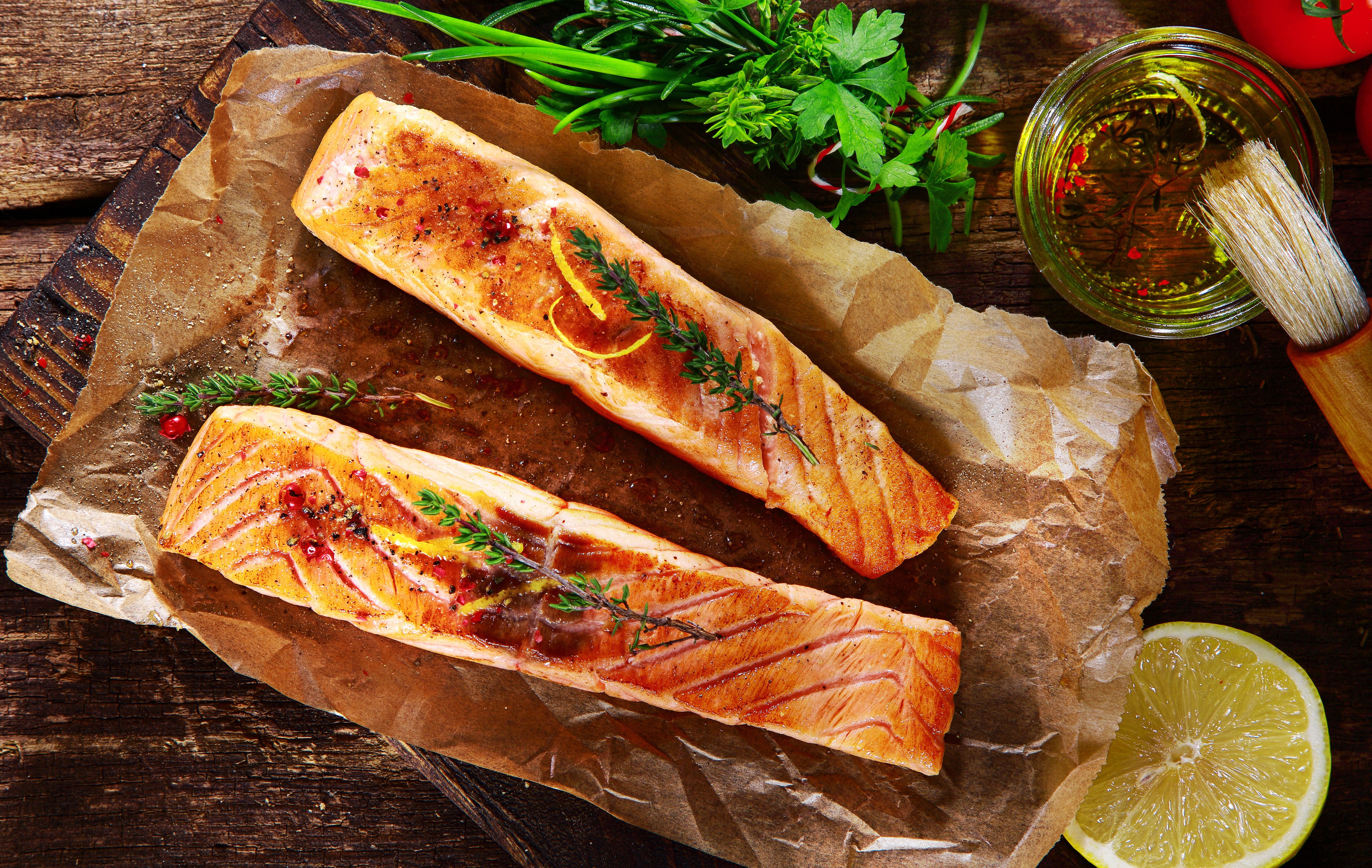 Two salmon fillets with herbs and lemon on parchment paper HD Wallpaper