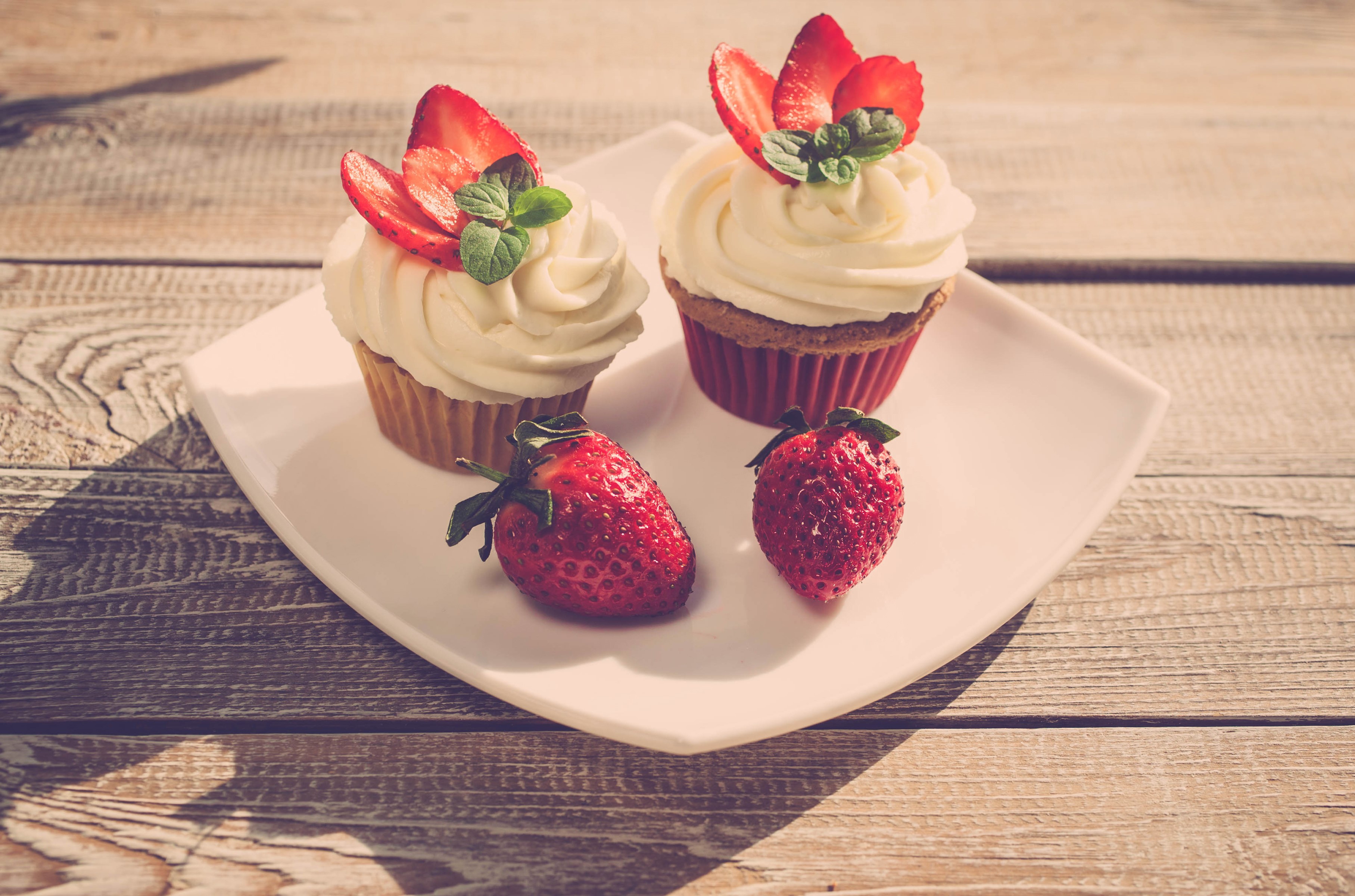 Two strawberry cupcakes with cream and strawberries on a plate HD Wallpaper