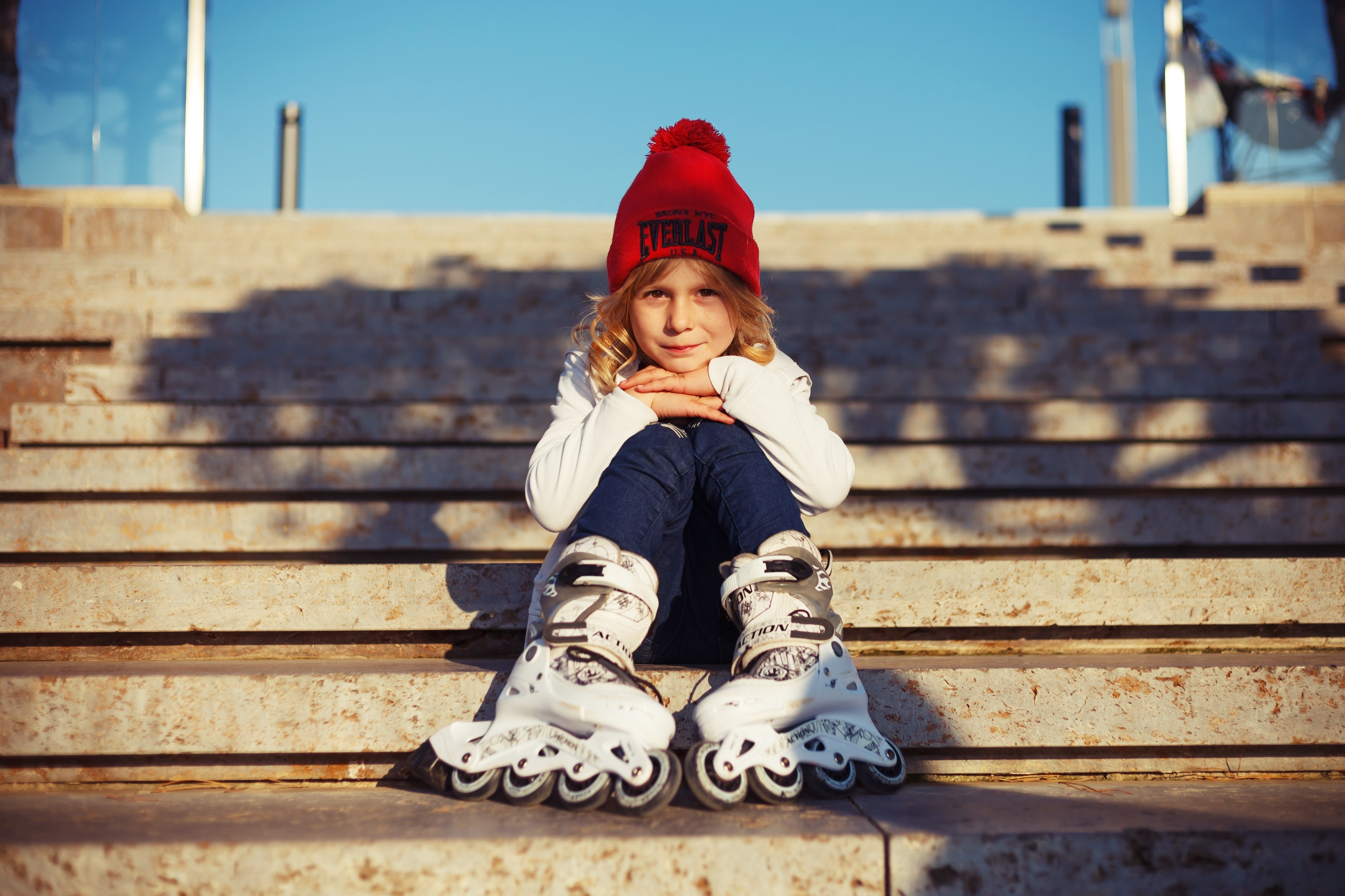 Girl in Everlast winter hat and roller skates sitting on steps HD Wallpaper
