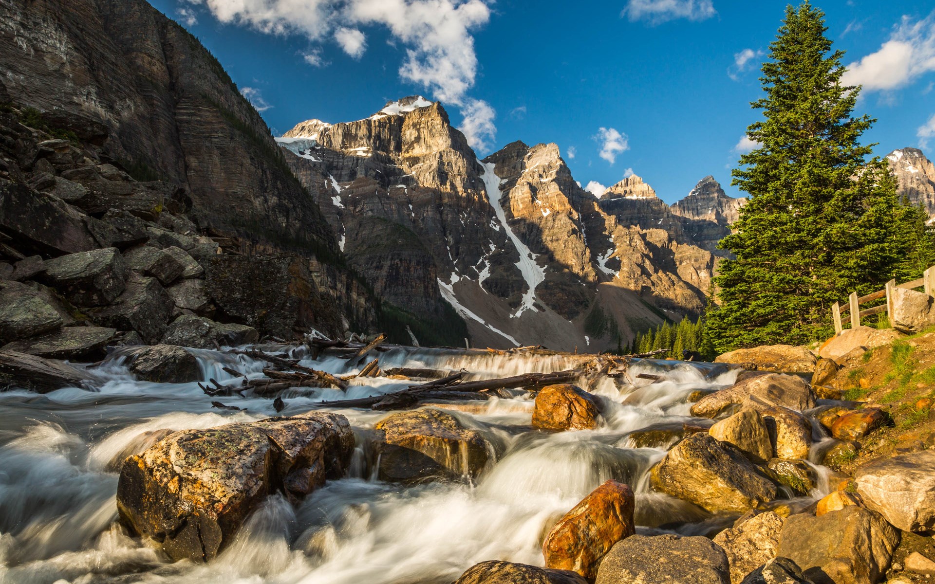 River flowing through rocky terrain with mountains and trees HD Wallpaper
