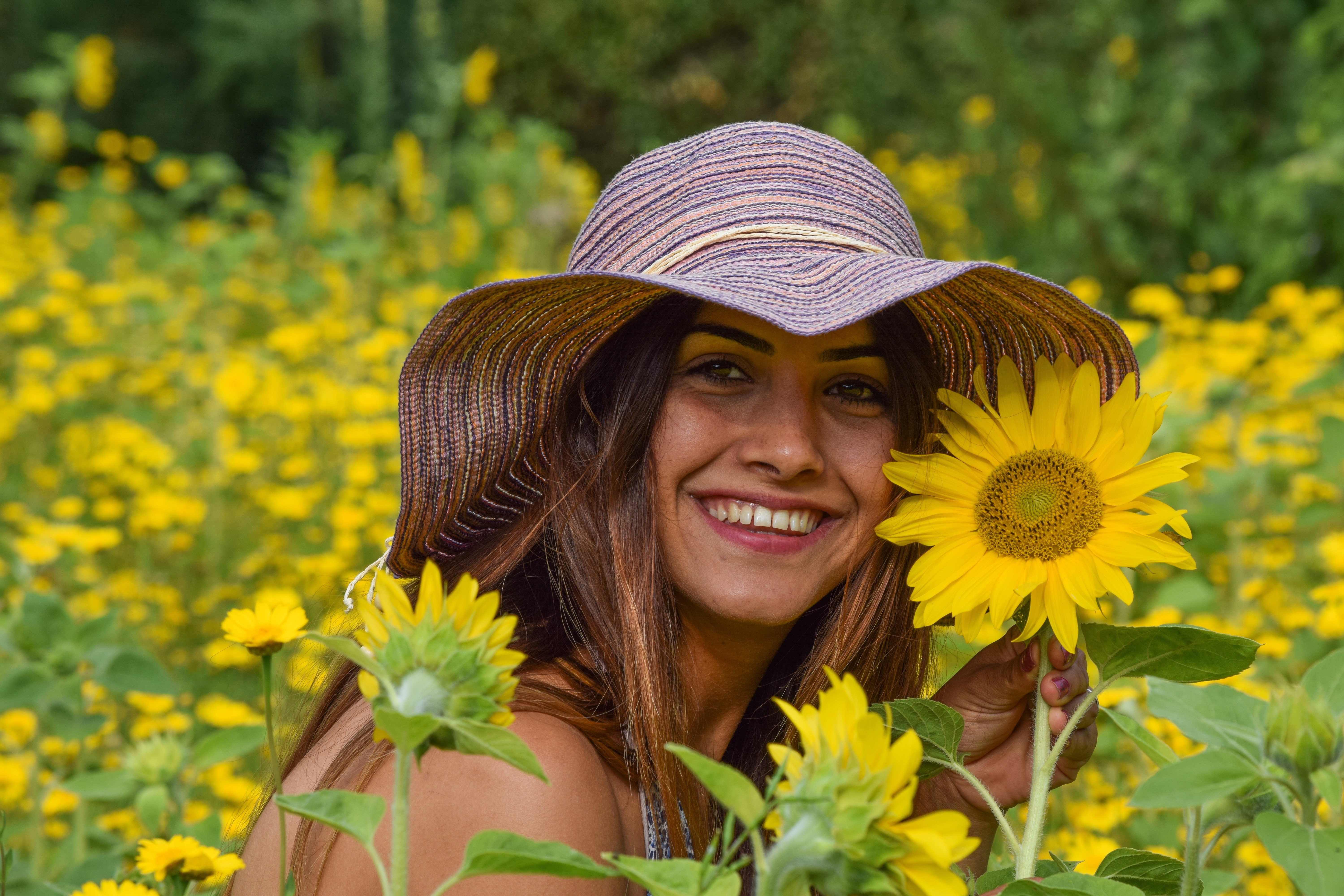 Woman in a hat smiling in a sunflower field HD Wallpaper