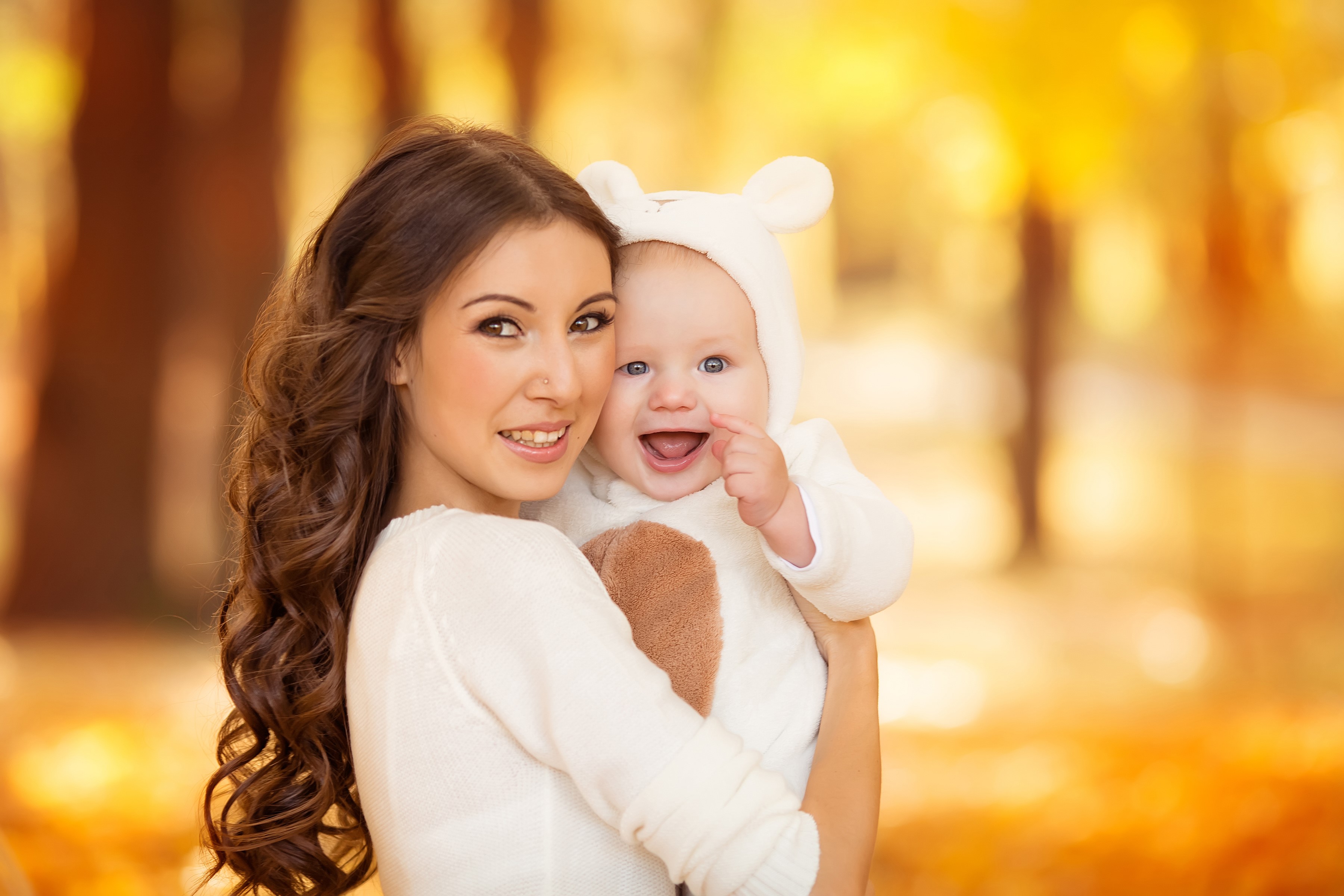 Mother holding a smiling baby in a bear costume HD Wallpaper
