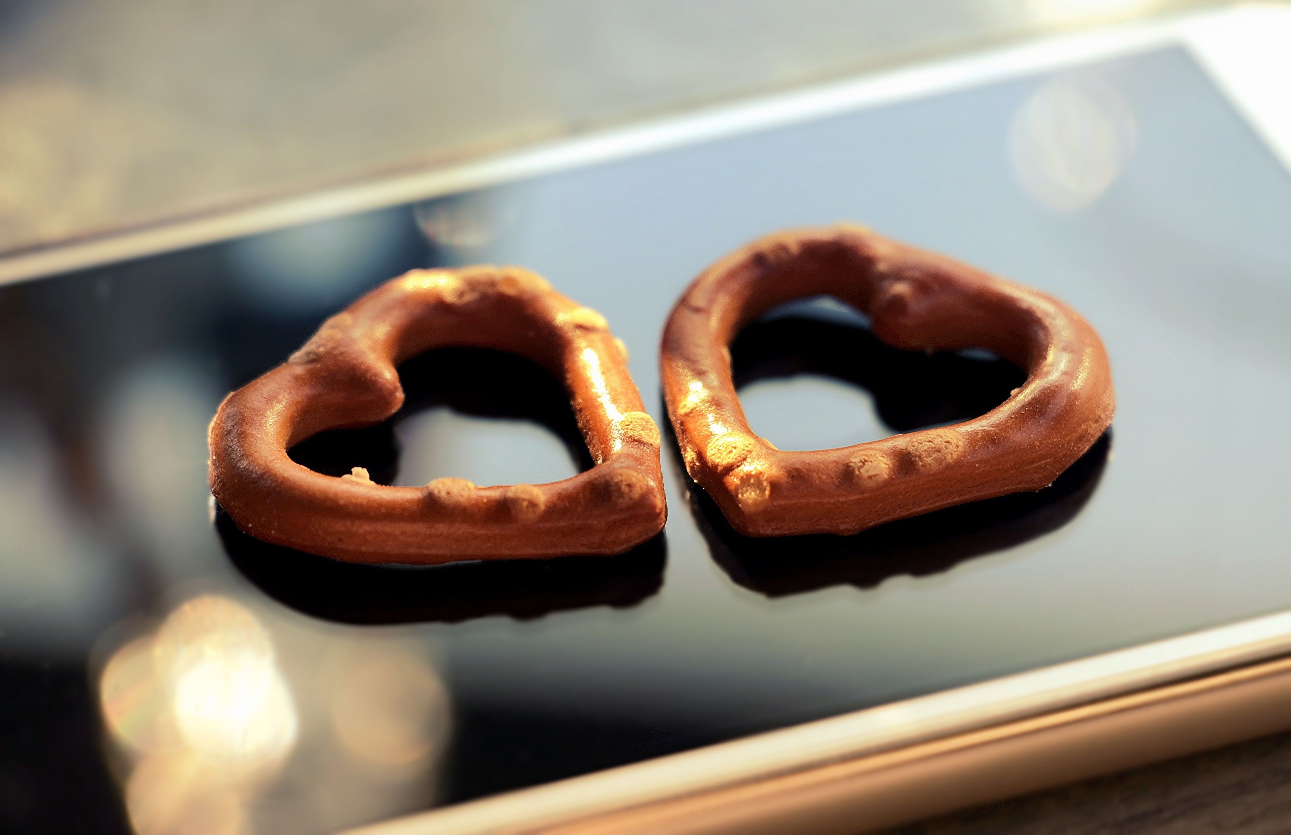Two heart-shaped chocolate pretzels on a smartphone HD Wallpaper