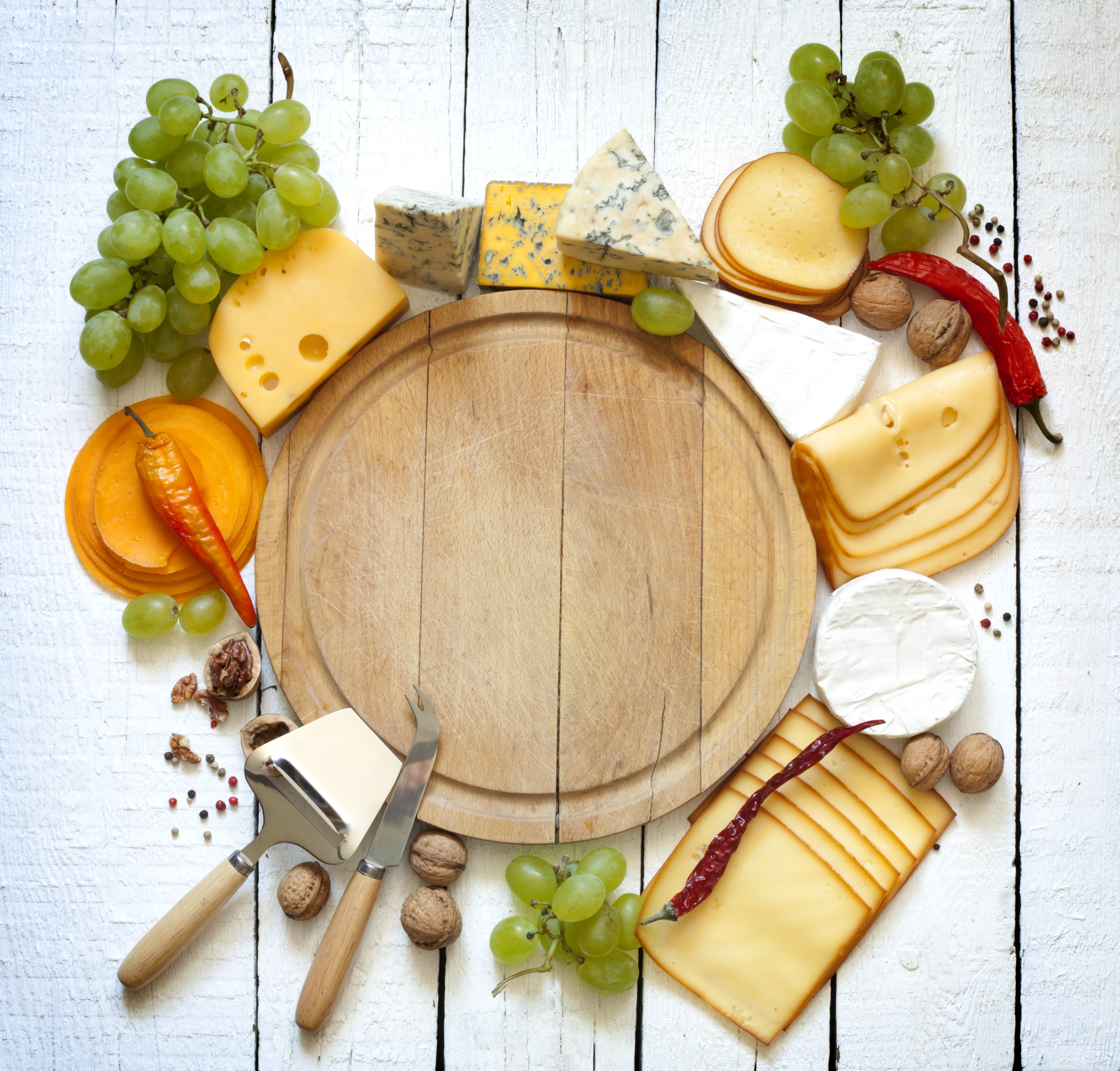 Cheese platter with grapes, nuts, and chili peppers on wood planks HD Wallpaper