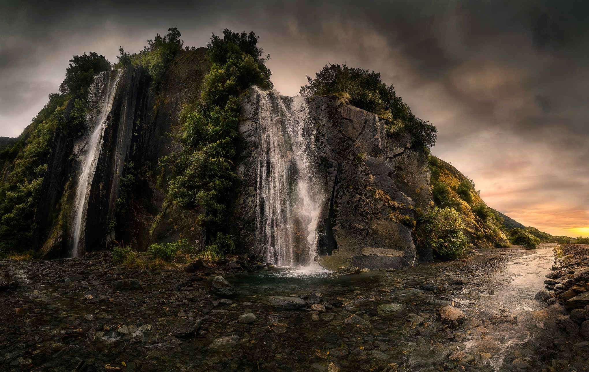 Waterfall cascading down a rocky cliff in Franz Josef Valley, New Zealand HD Wallpaper