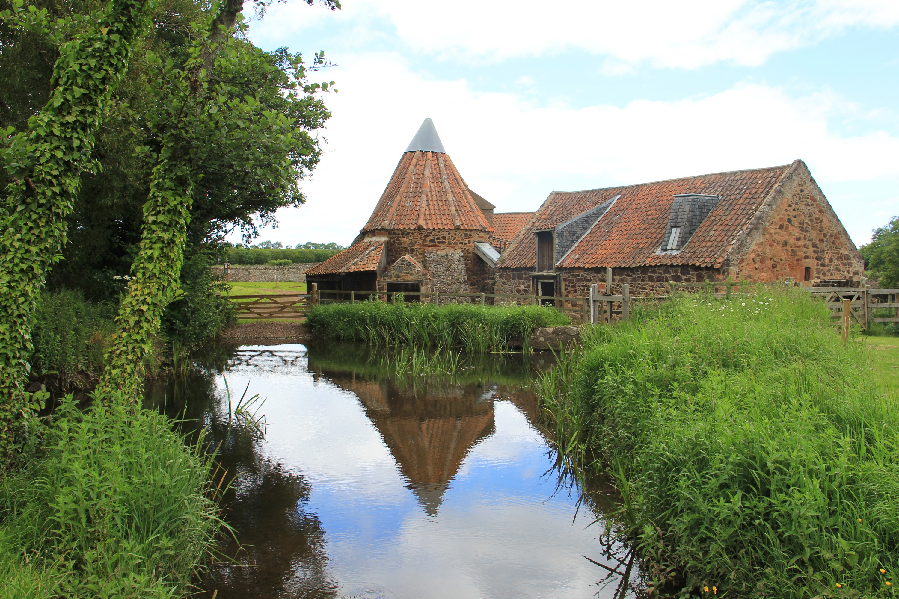 Stone buildings and a conical tower reflected in water HD Wallpaper