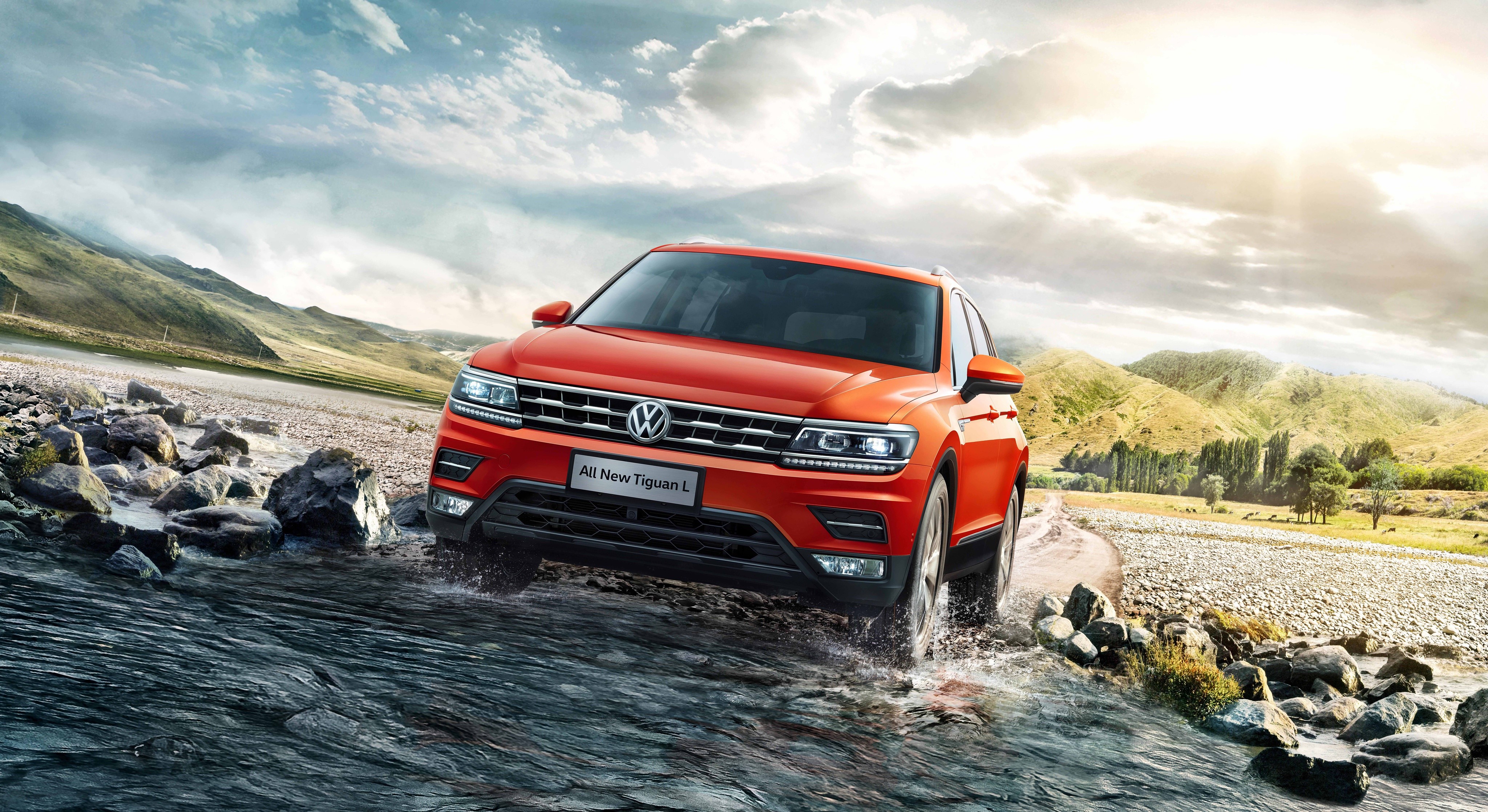 Orange Volkswagen Tiguan L driving through water HD Wallpaper