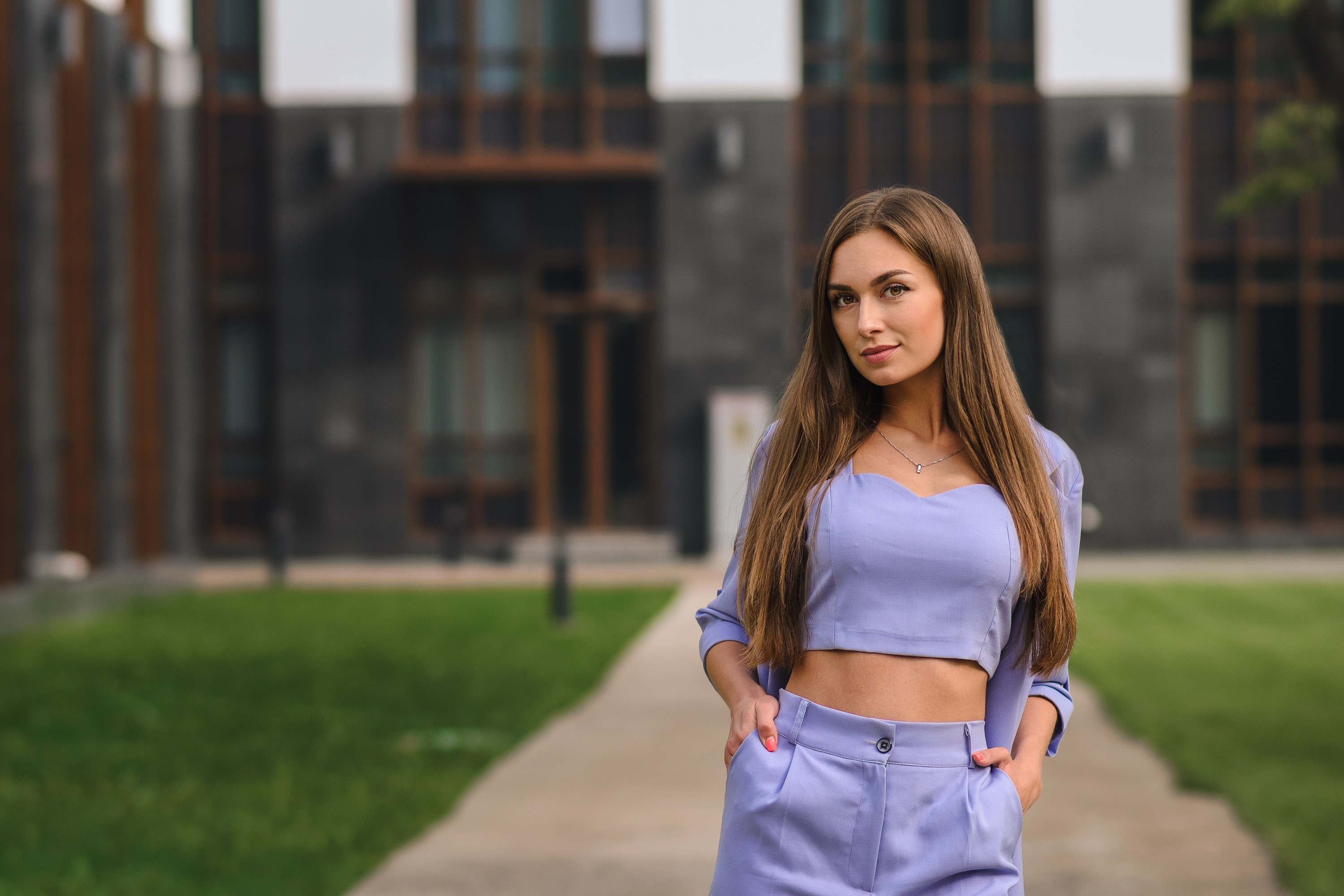 Brown-haired woman in a purple outfit standing outside a modern building HD Wallpaper