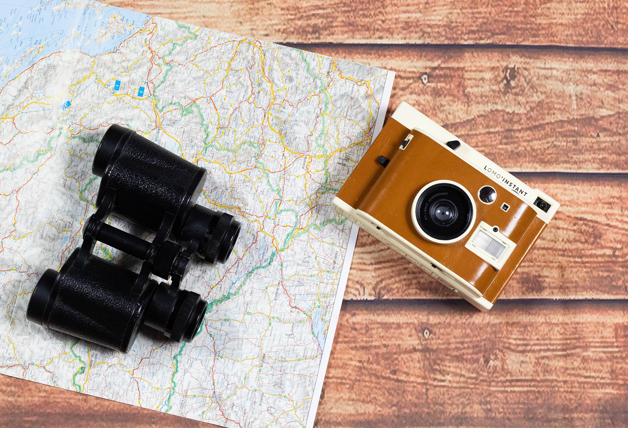 Binoculars and camera on a map HD Wallpaper