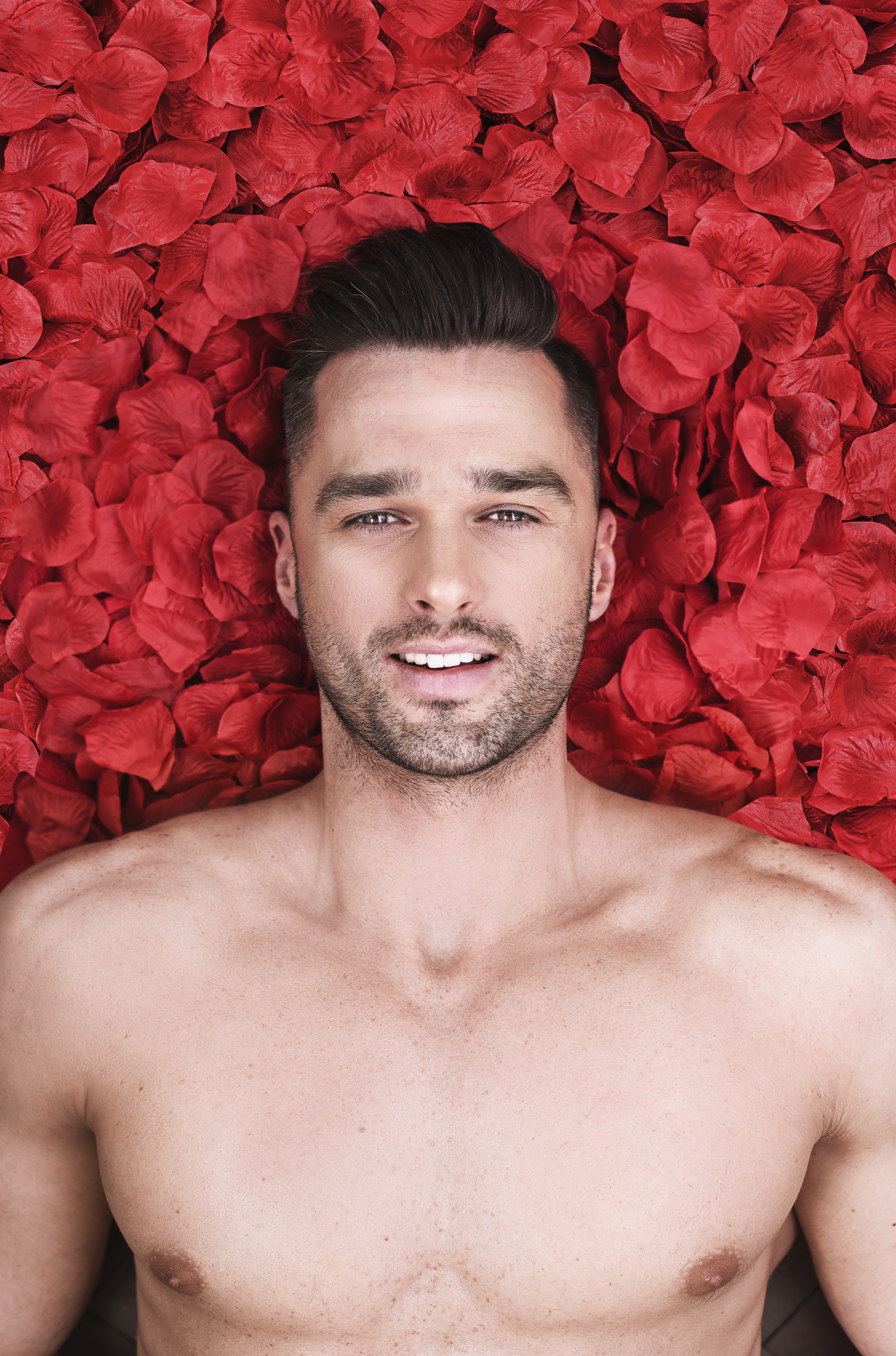 Man lying on red petals HD Phone Wallpaper