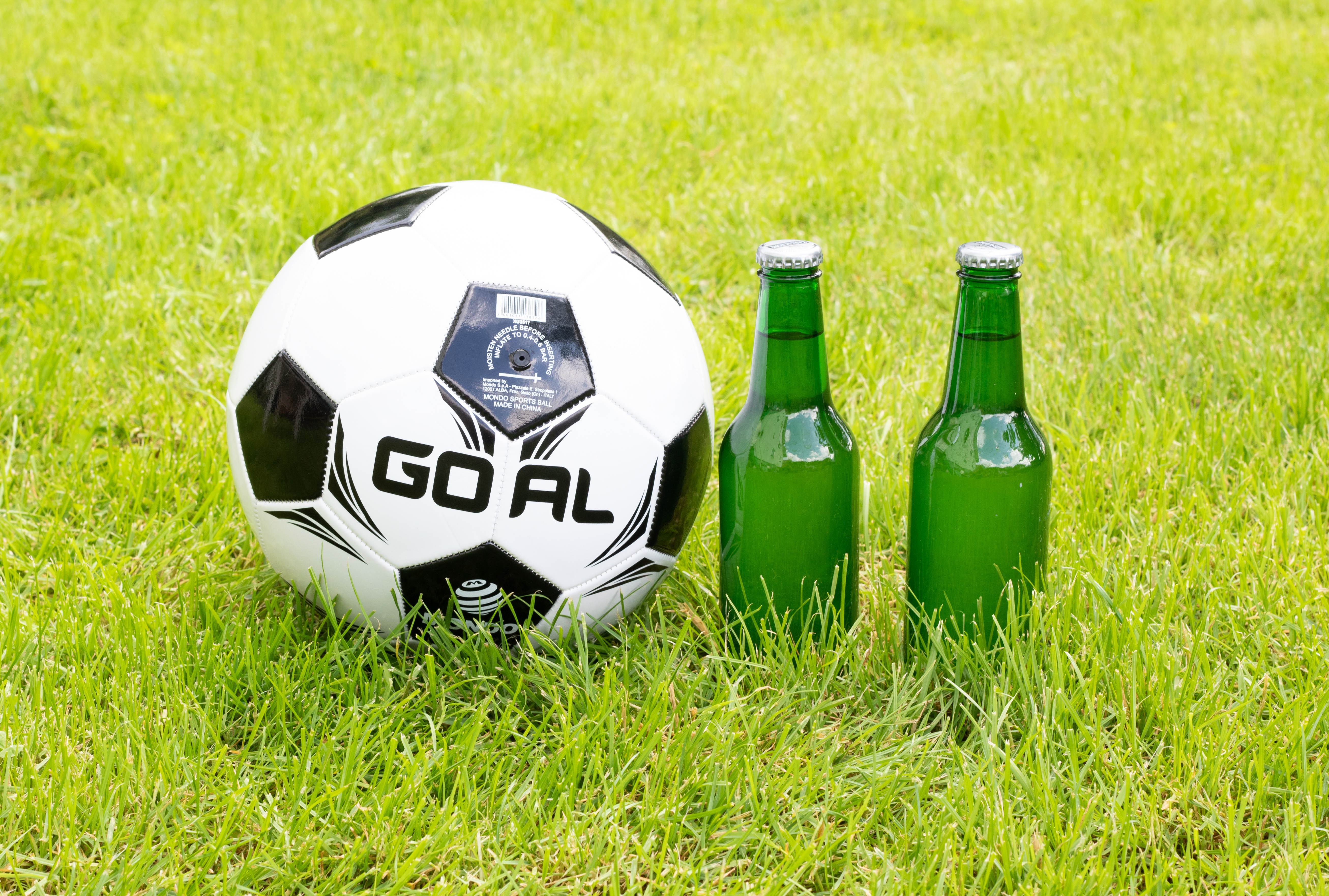 Soccer ball and two beer bottles on grass HD Wallpaper