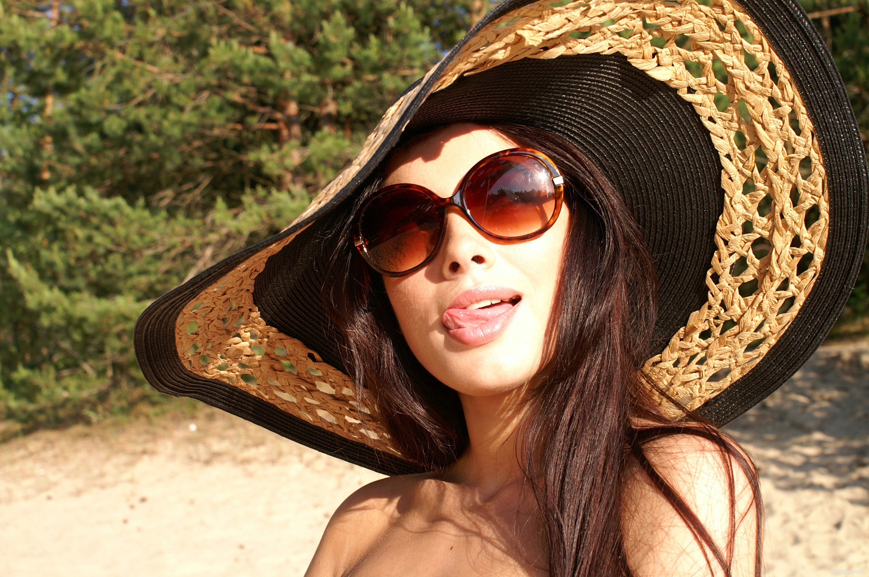 Woman in a wide-brimmed hat and sunglasses sticking out her tongue HD Wallpaper