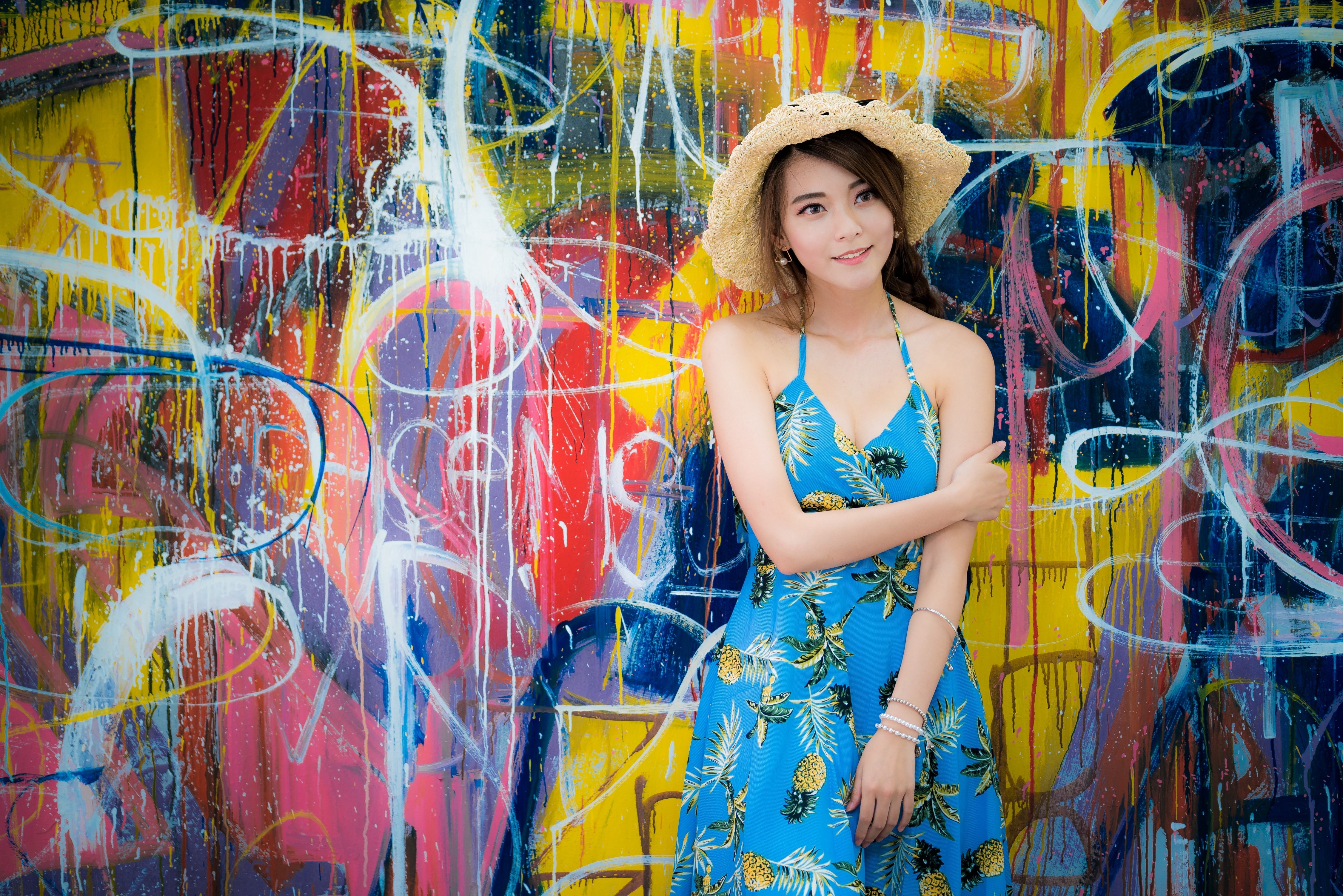 Asian woman in a blue dress and hat in front of graffiti wall HD Wallpaper