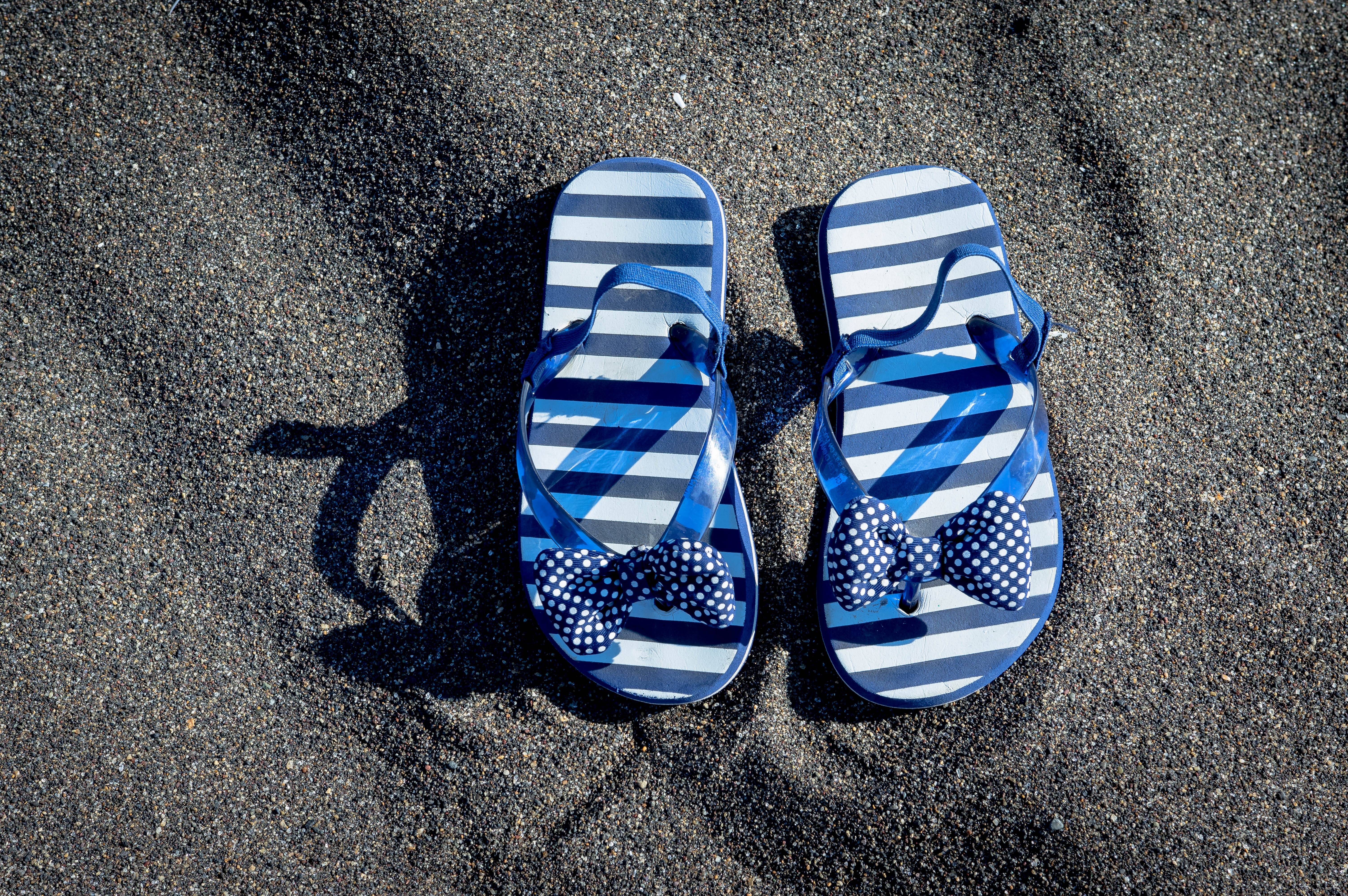 Blue striped flip-flops with bows on sand HD Wallpaper