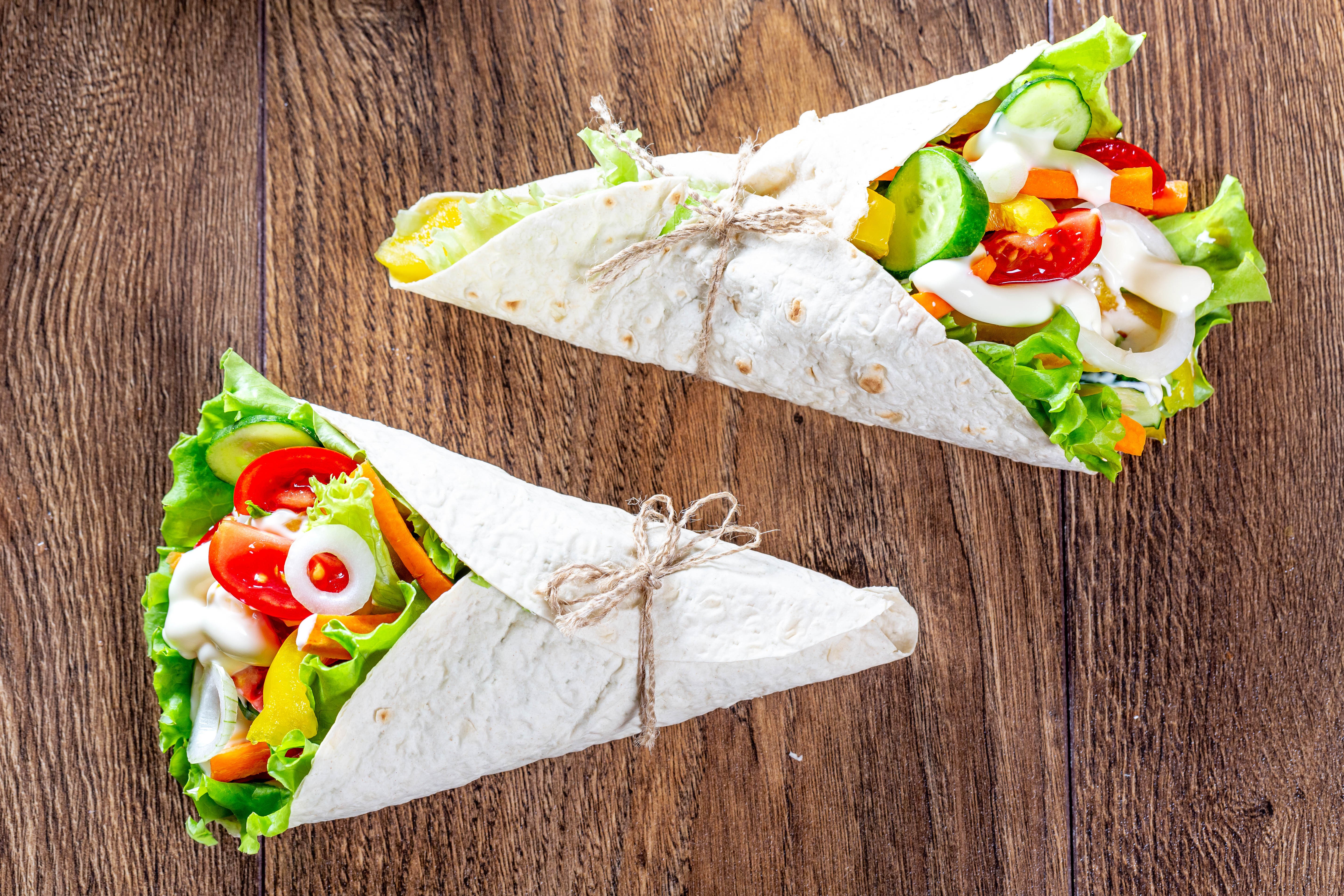 Two vegetable wraps on wooden planks HD Wallpaper