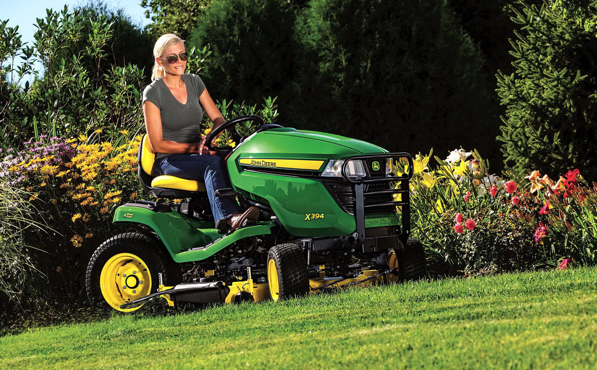 Woman on John Deere X394 lawn tractor mowing grass HD Wallpaper