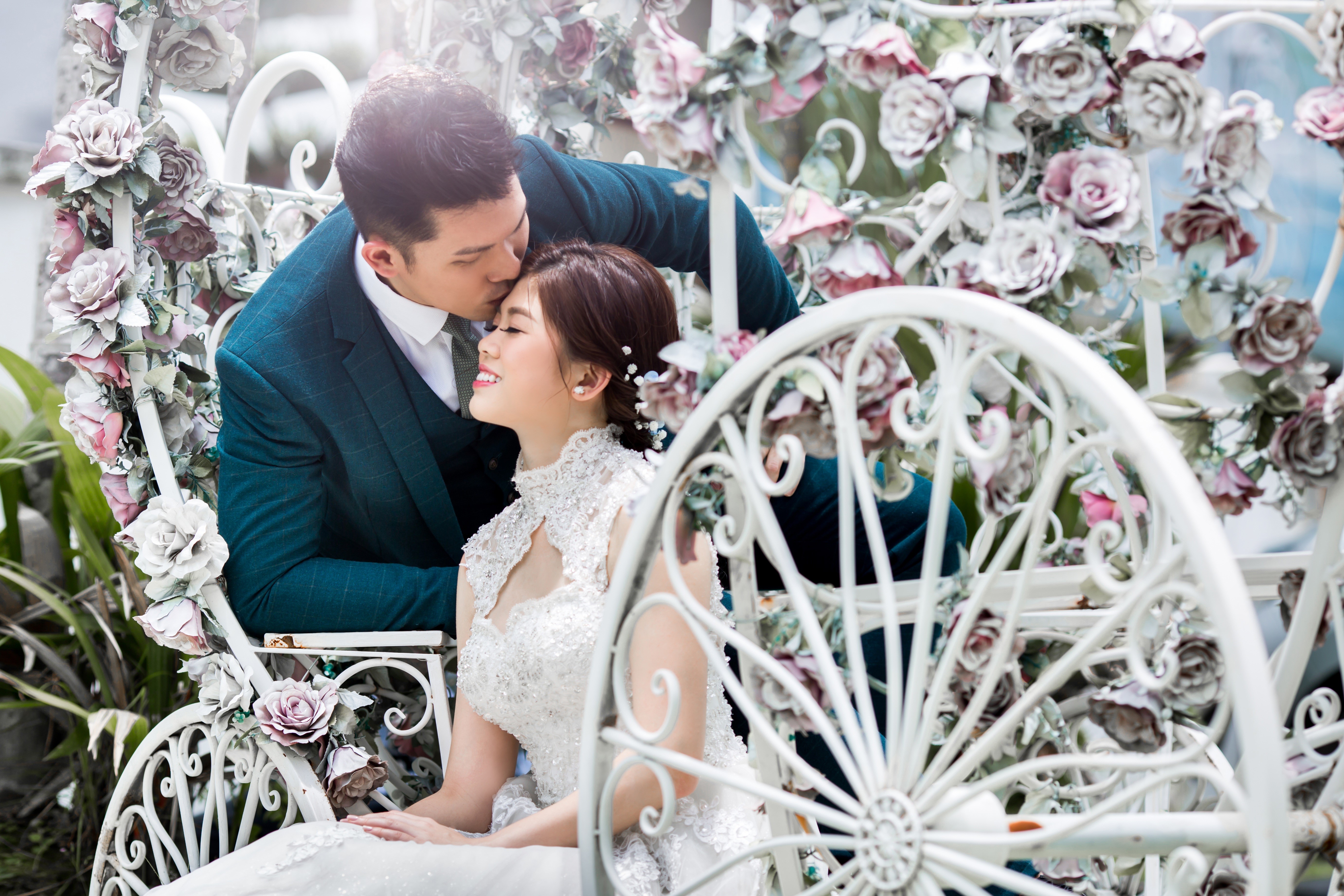 Couple in wedding attire kissing in a floral carriage HD Wallpaper