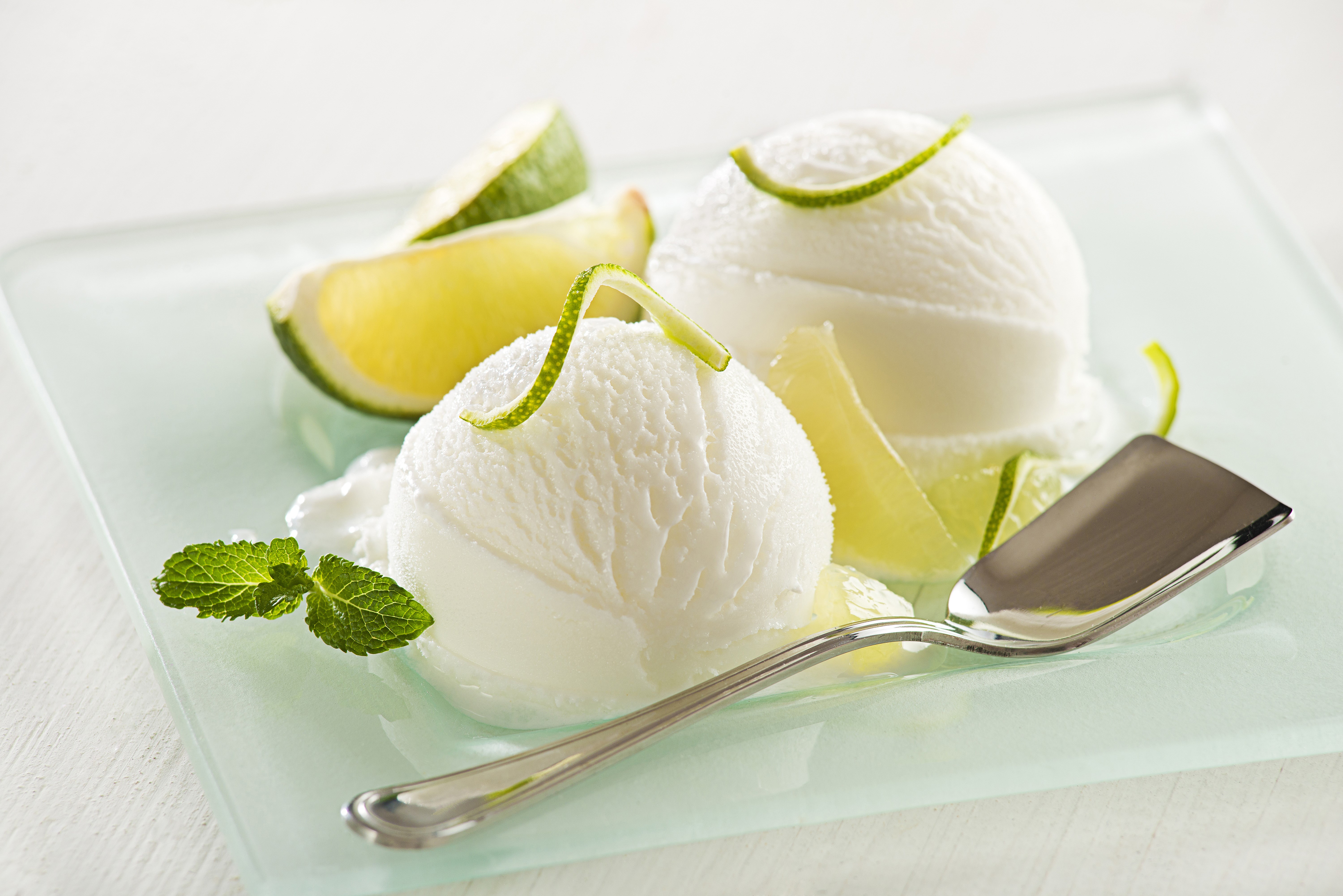 Two scoops of lime ice cream with lime wedges and mint HD Wallpaper