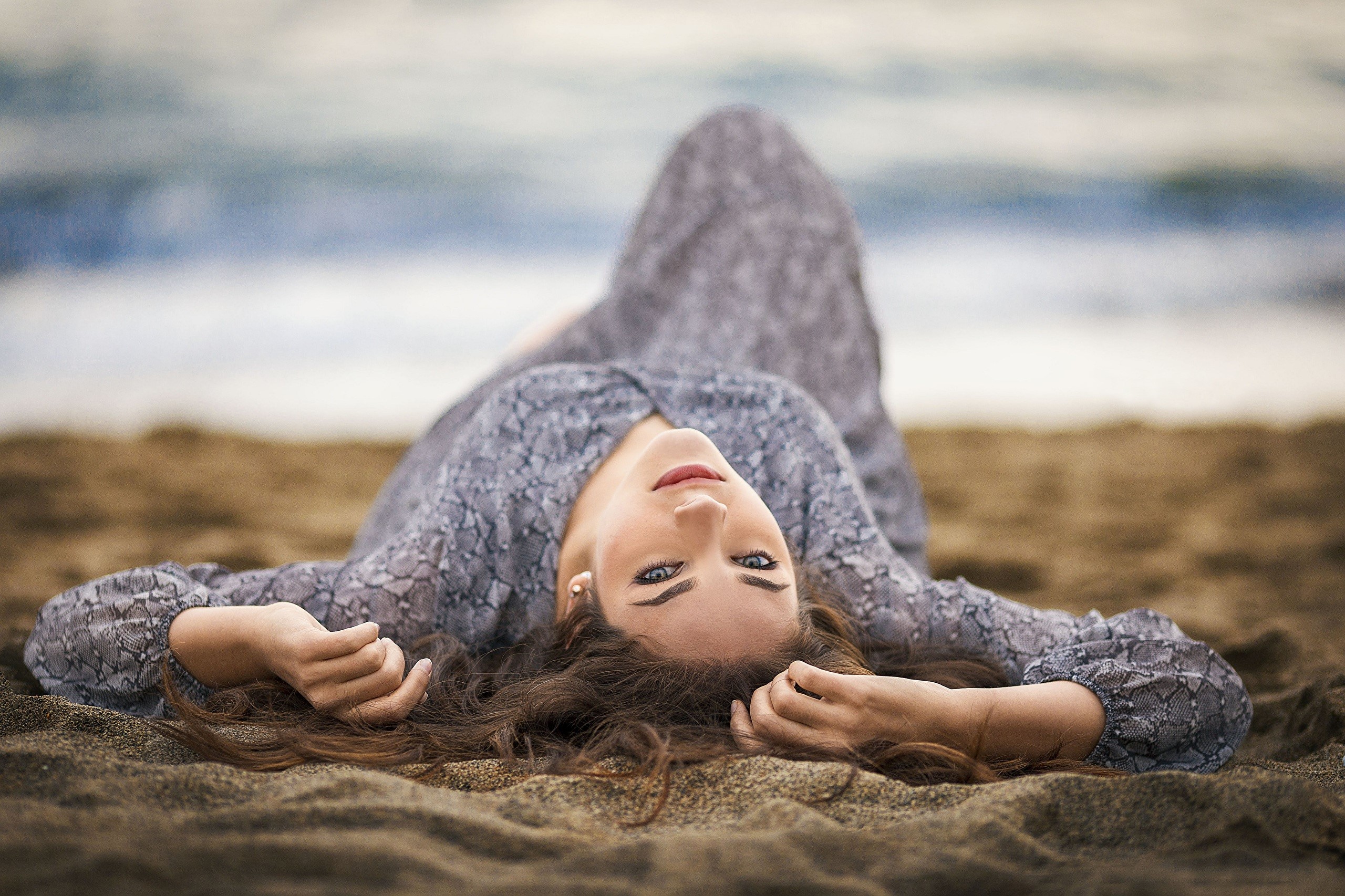 Woman in a dress lying on the sand at the beach HD Wallpaper