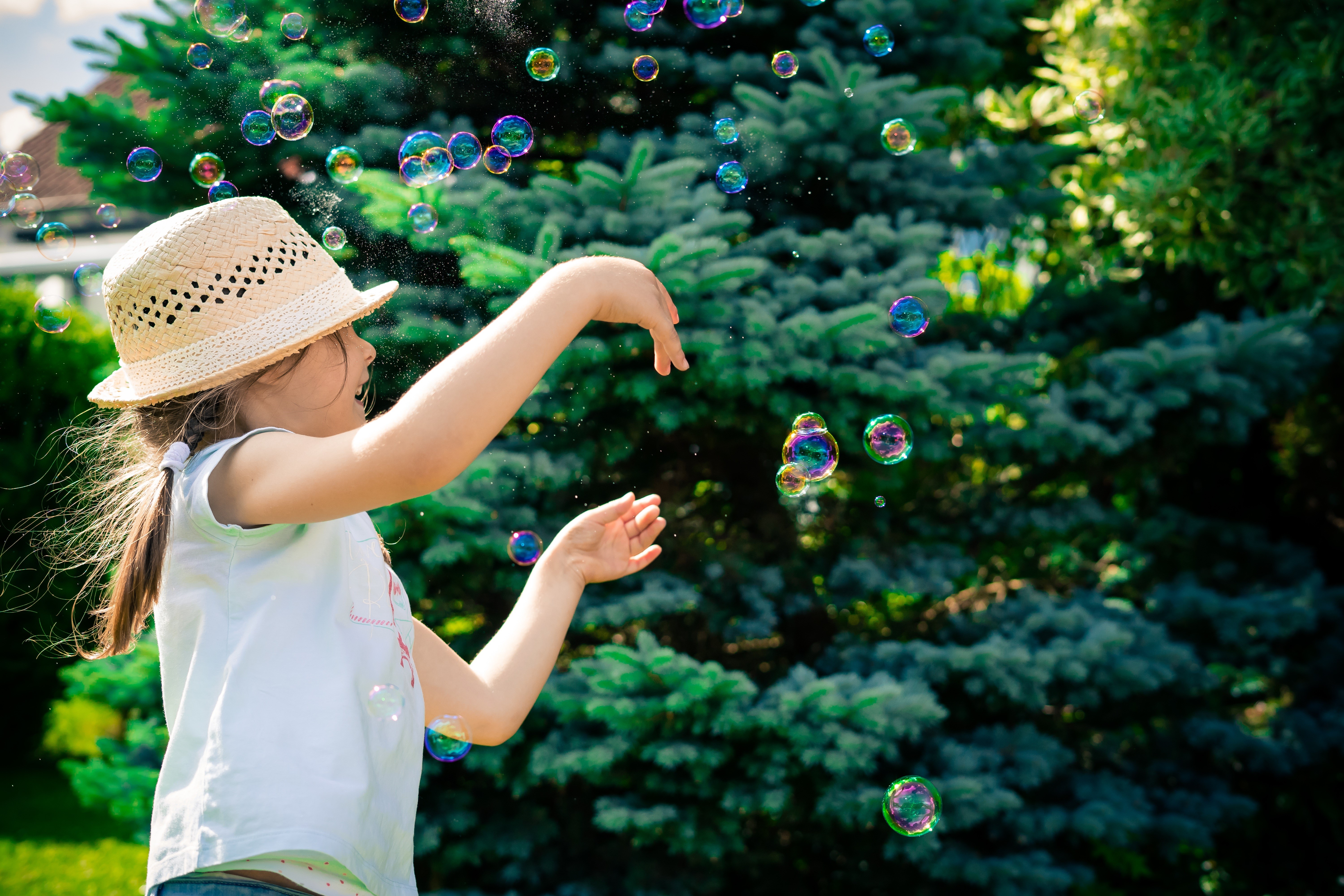 Little girl in hat blowing soap bubbles HD Wallpaper