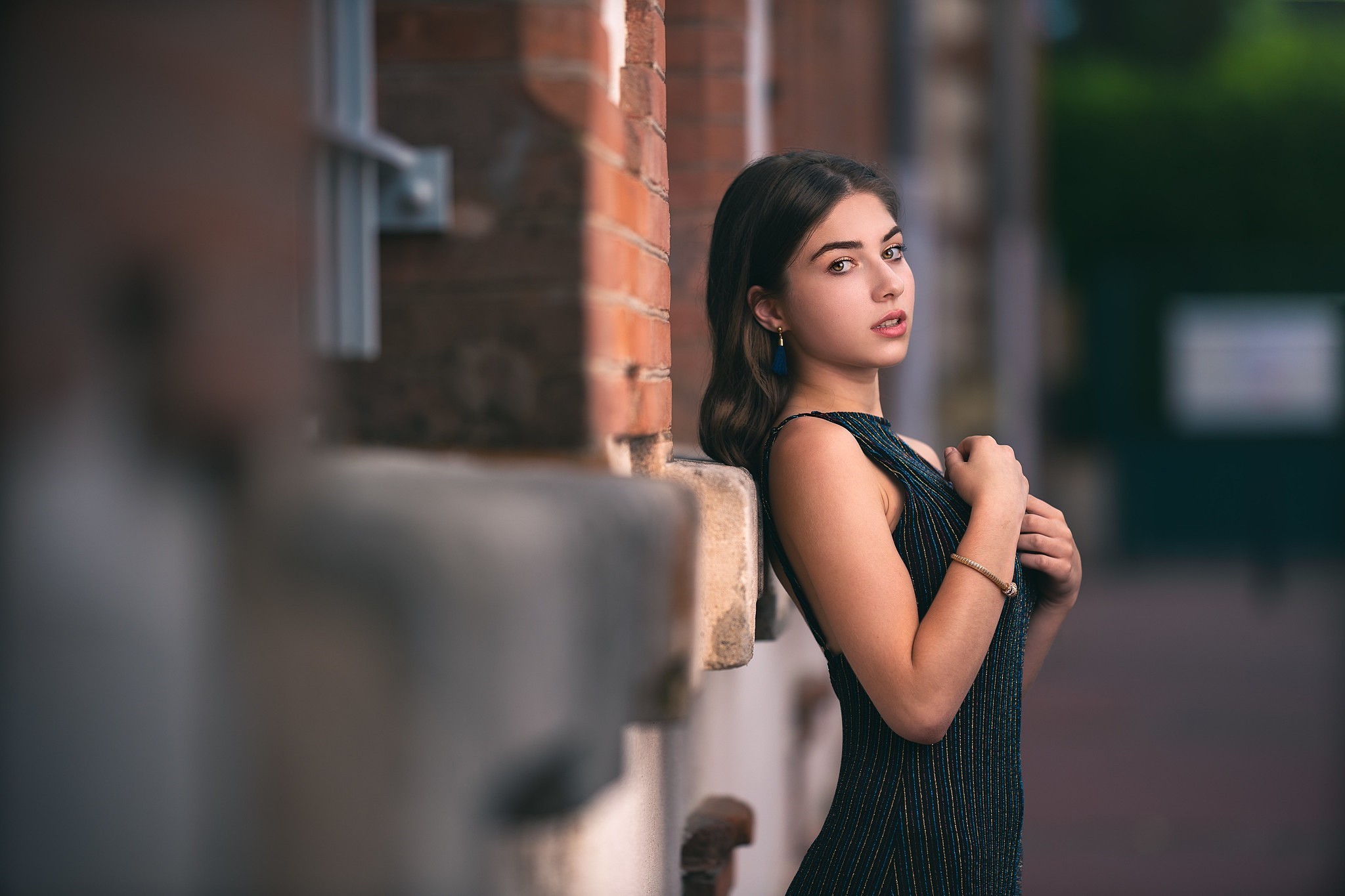 Woman leaning against a brick wall HD Wallpaper