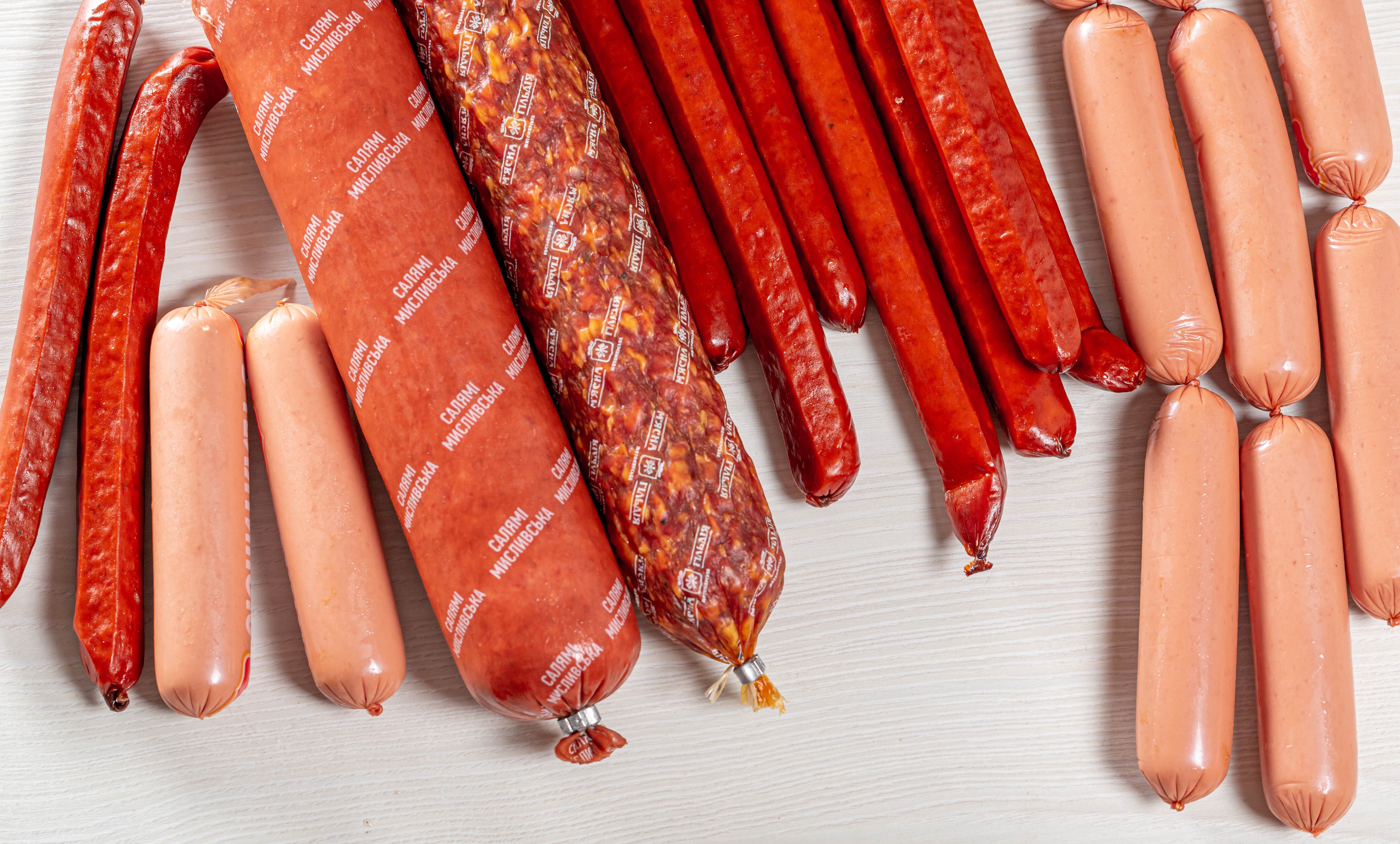 Assortment of sausages and Vienna sausages on a white surface HD Wallpaper