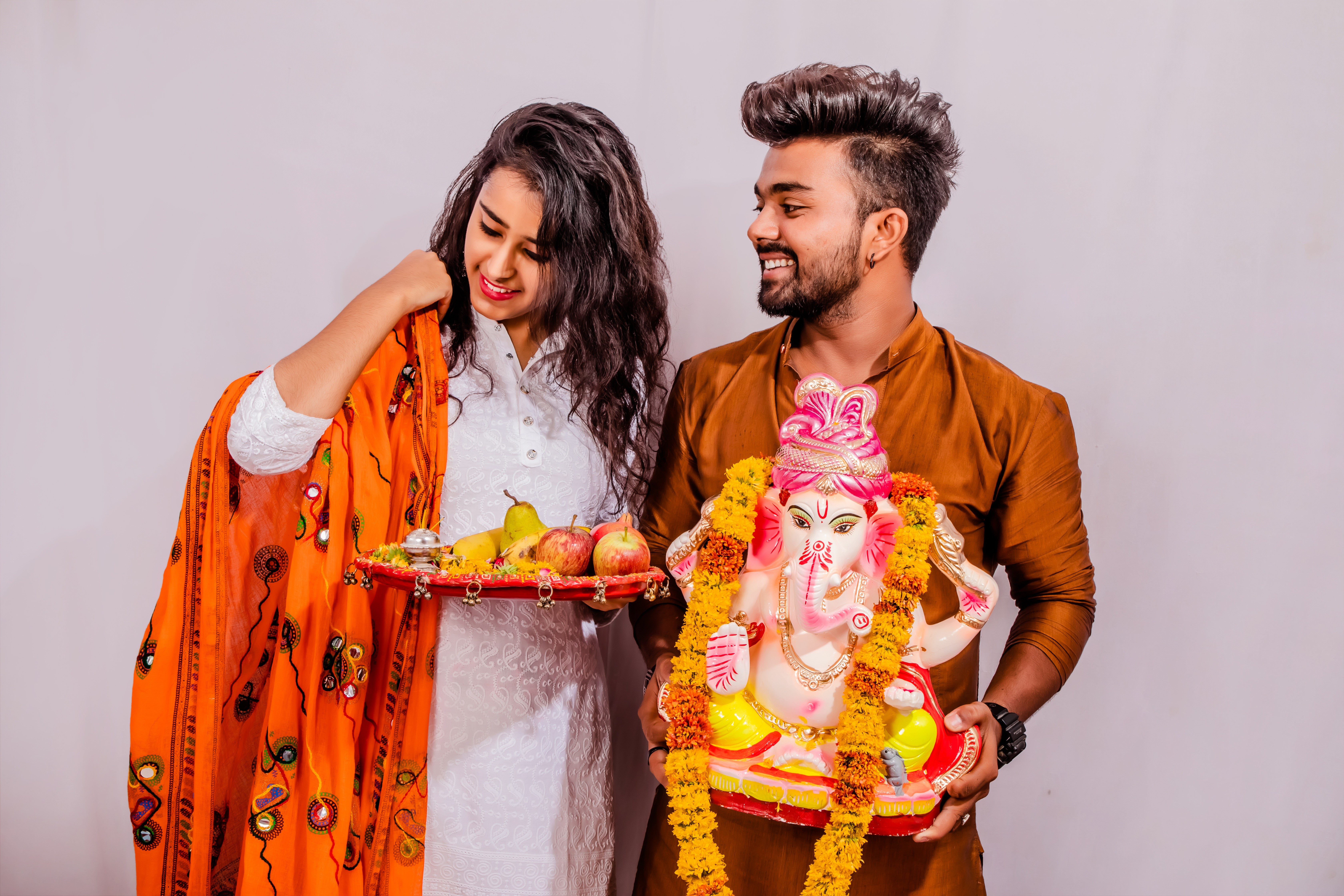 Couple celebrating Ganesh Chaturthi with idol and fruits HD Wallpaper